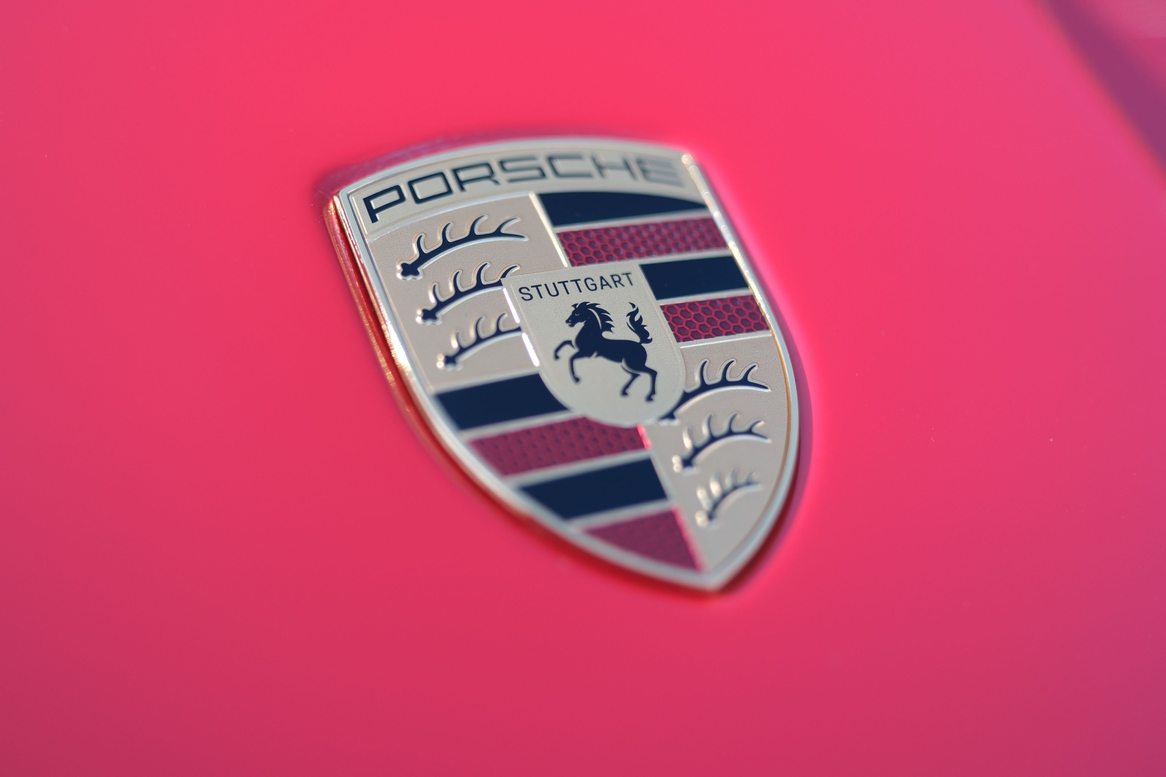 Der Schriftzug des Stuttgarter Sportwagenherstellers Porsche auf der Motorhaube eines roten Porsche-Sportwagens.
