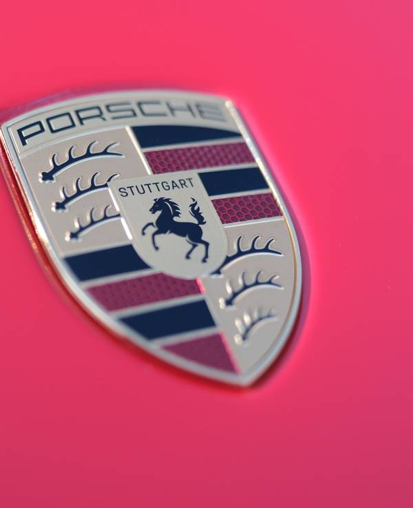 Der Schriftzug des Stuttgarter Sportwagenherstellers Porsche auf der Motorhaube eines roten Porsche-Sportwagens.