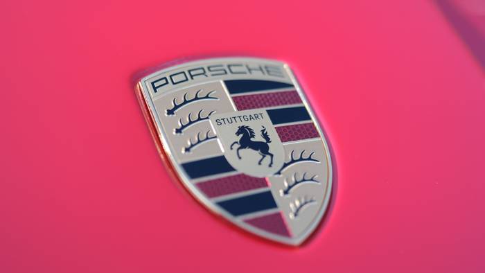 Der Schriftzug des Stuttgarter Sportwagenherstellers Porsche auf der Motorhaube eines roten Porsche-Sportwagens.
