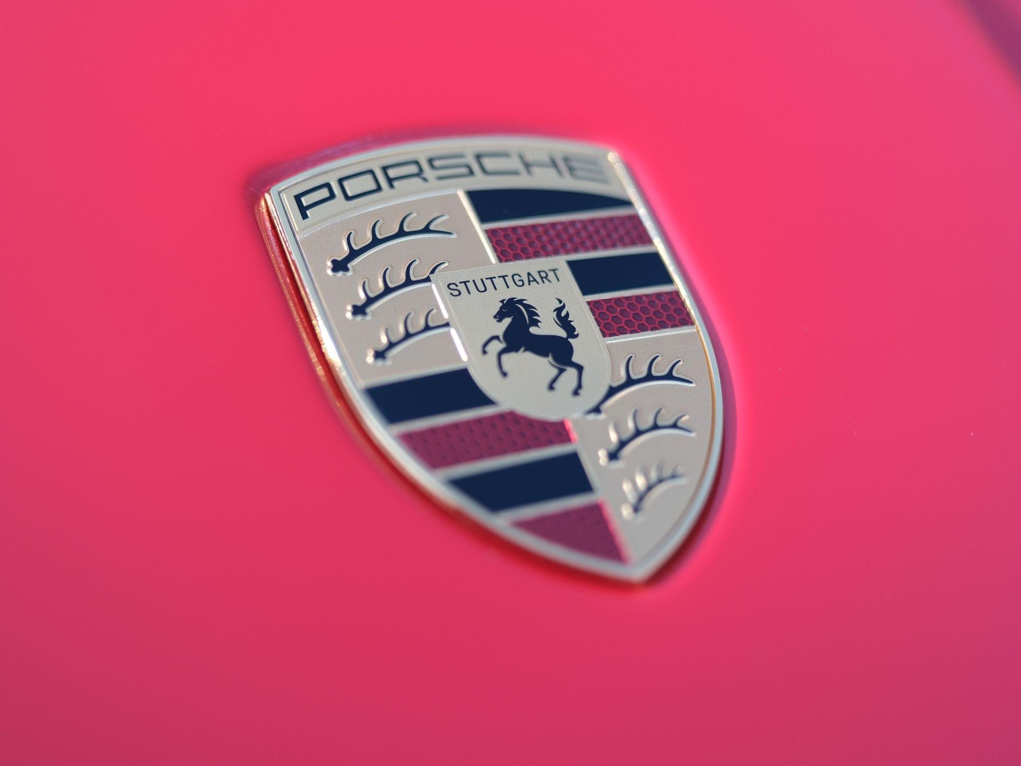Der Schriftzug des Stuttgarter Sportwagenherstellers Porsche auf der Motorhaube eines roten Porsche-Sportwagens.