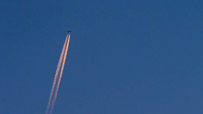 Am blauen Himmel fliegt ein Flugzeug und hinterlässt Kondensstreifen. (Symbolbild)