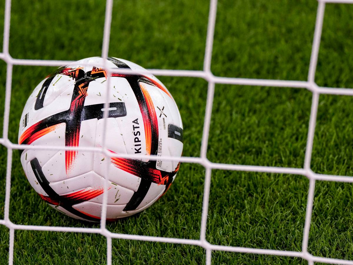 Ein Ball der Marke KIPSTA Decathlon Official Match Football liegt im Tor hinter dem Tornetz, offizieller Spielball, official Match Ball.