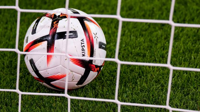 Ein Ball der Marke KIPSTA Decathlon Official Match Football liegt im Tor hinter dem Tornetz, offizieller Spielball, official Match Ball.