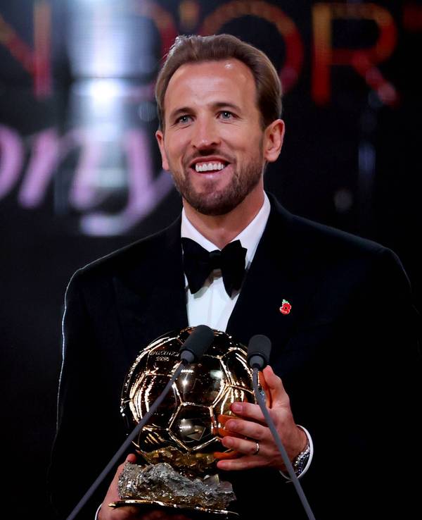Harry Kane lächelt mit der Ballon D`Or Trophäe in der Hand.