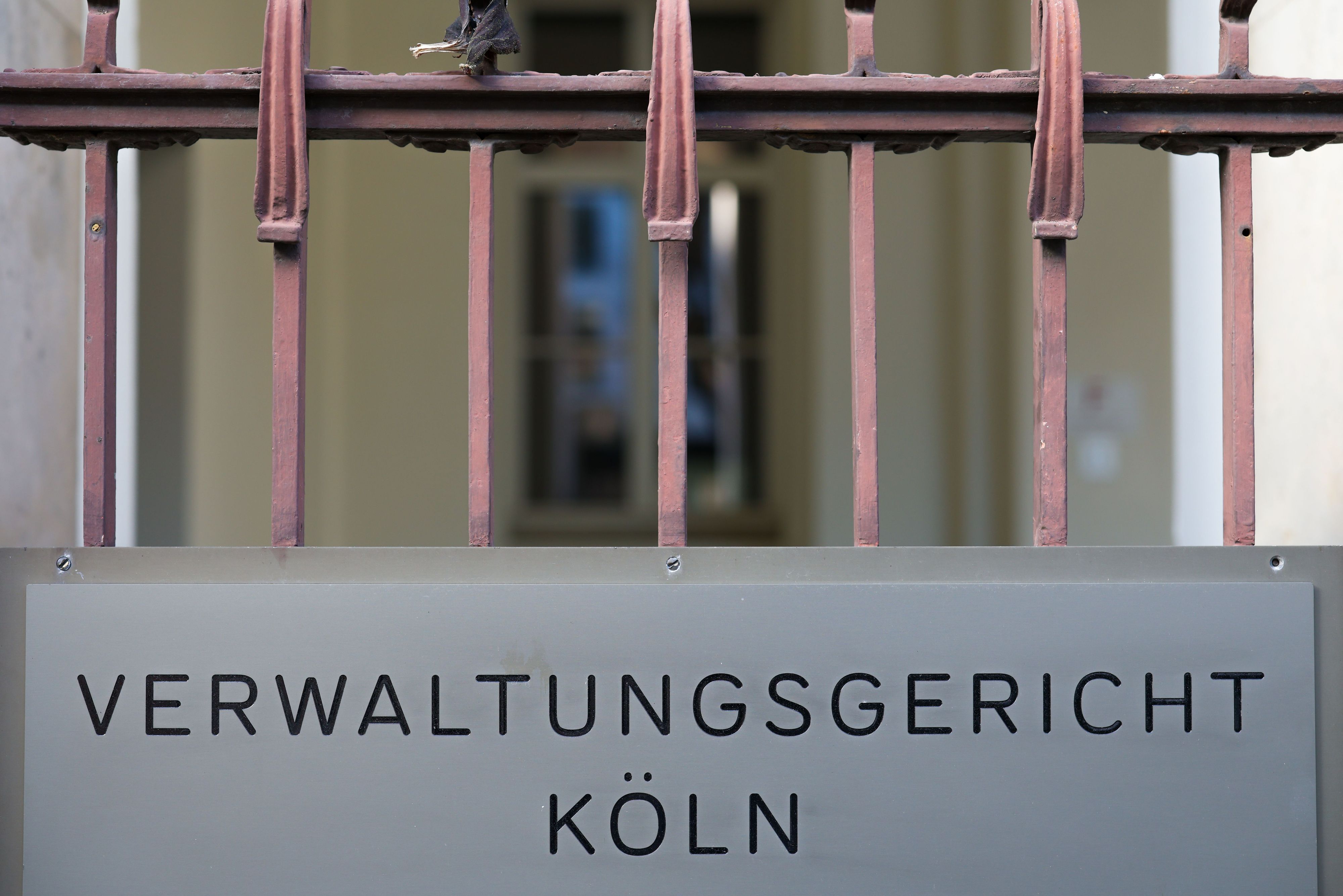 Ein Schild hängt am Eingang zum Verwaltungsgericht in Köln. +
