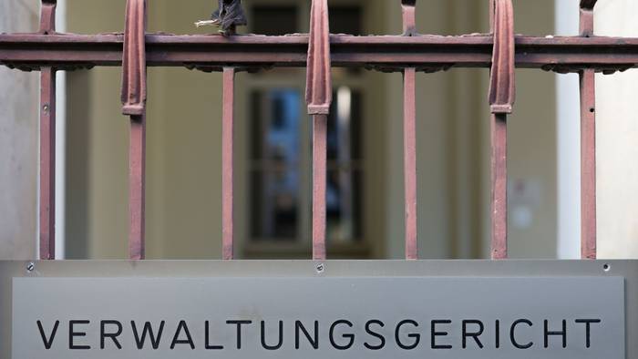 Ein Schild hängt am Eingang zum Verwaltungsgericht in Köln. +
