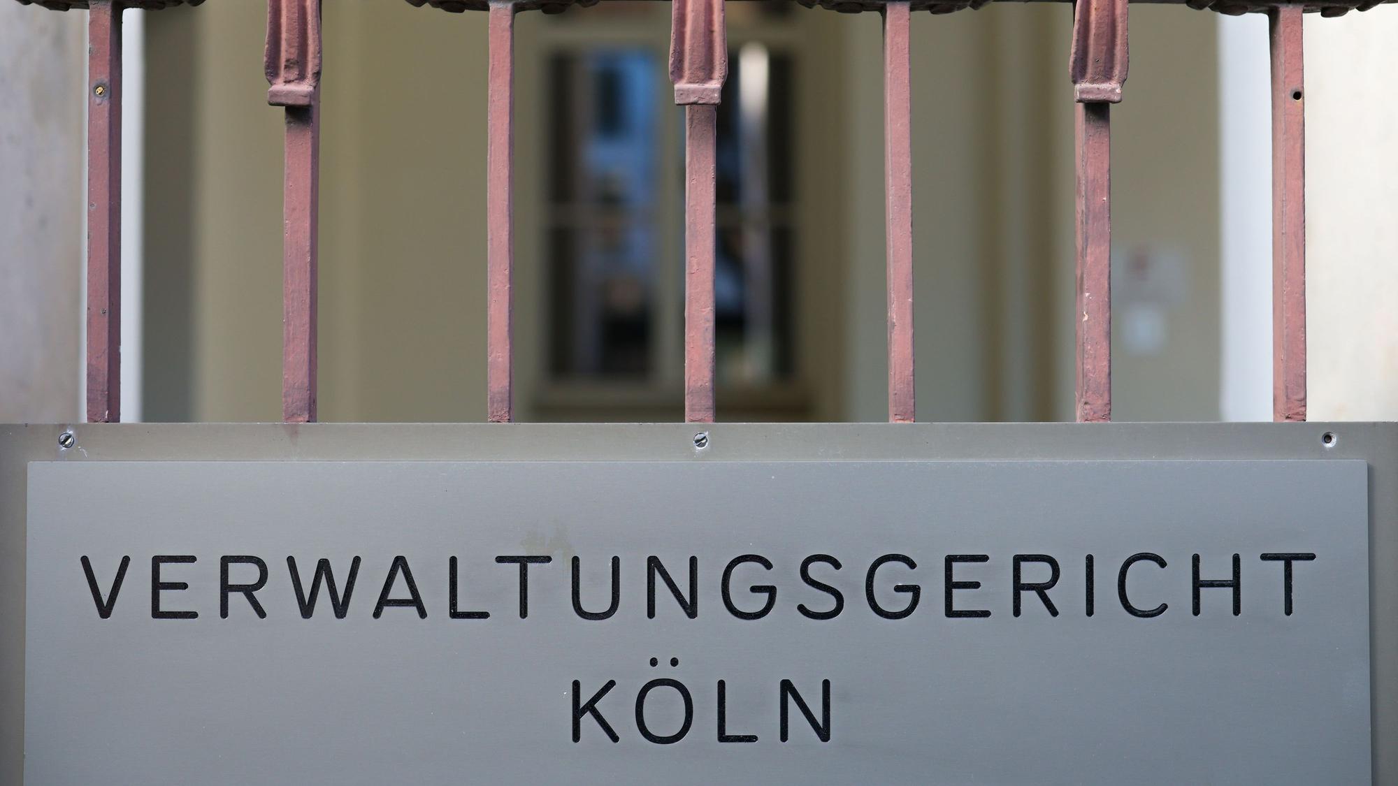 Ein Schild hängt am Eingang zum Verwaltungsgericht in Köln. +