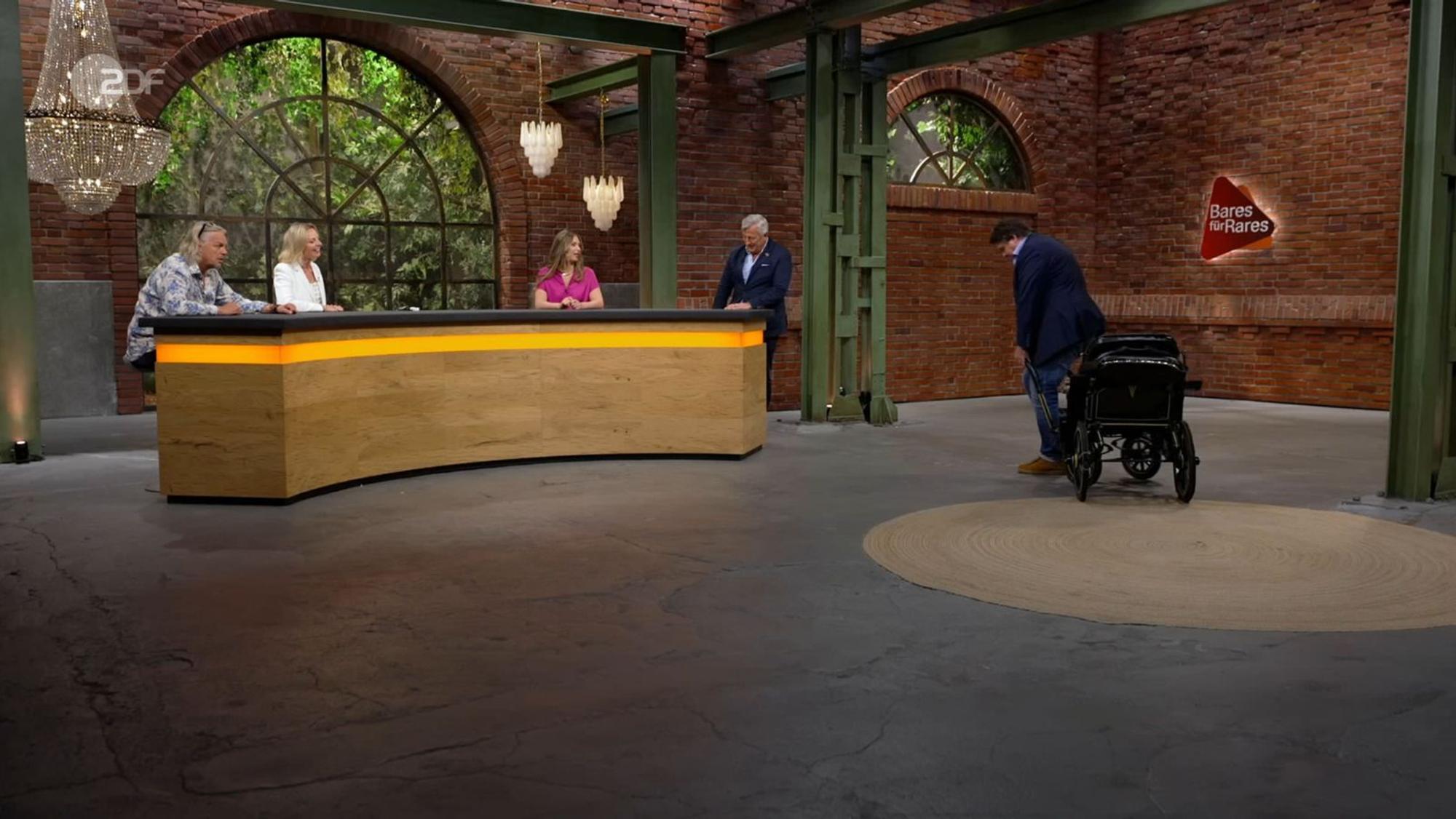 Daniel Meyer musste in die Knie gehen, um die Kutsche testweise zu ziehen: „Für Menschen ist es, glaube ich, nicht.“ Susanne Steiger neckte ihn: „Steht dir, Daniel.“ Sarah Schreiber machte ebenfalls einen Scherz ... (Bild: ZDF)