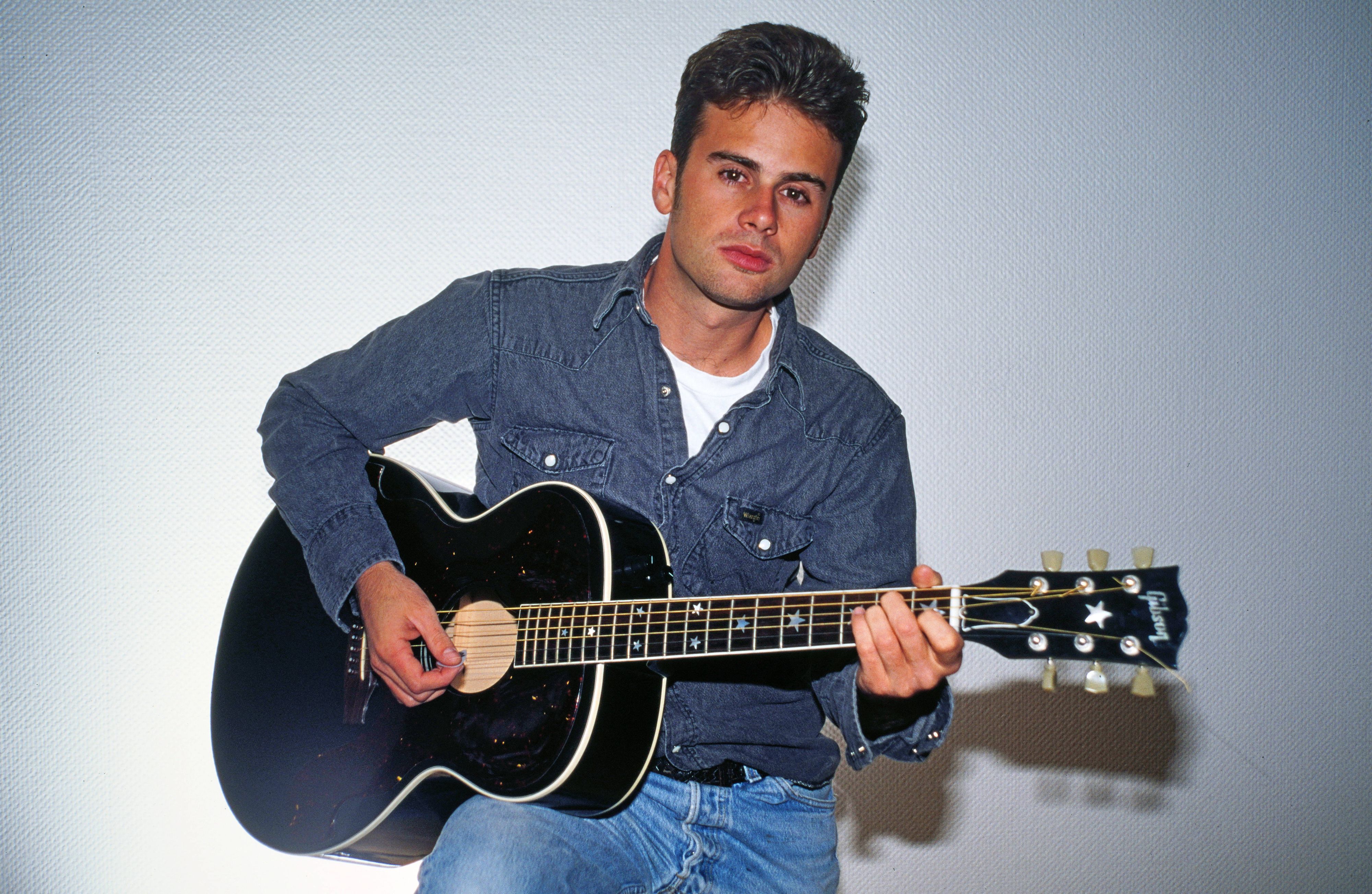Jamie Walters posiert mit Gitarre.