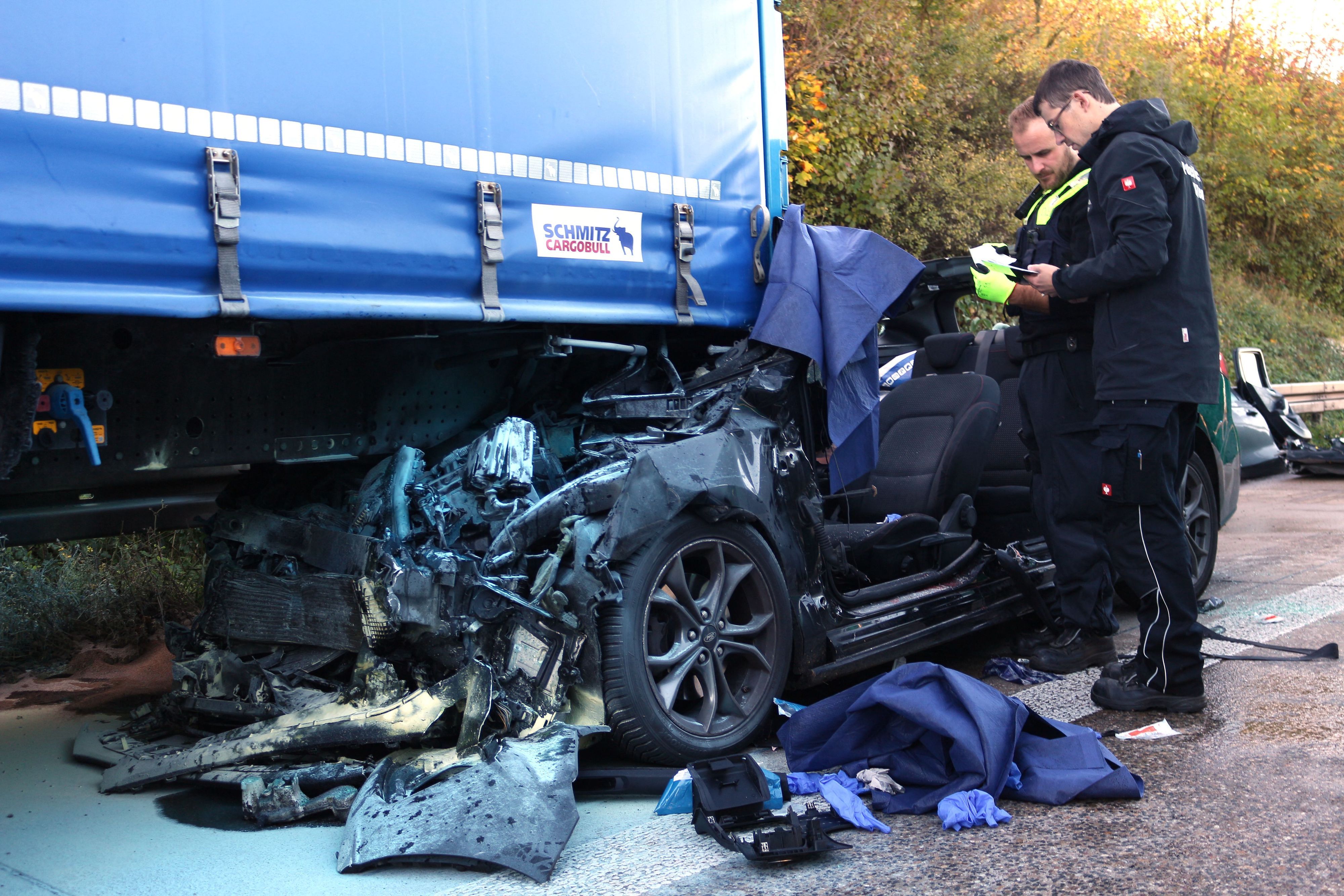 Einsatzkräfte der Polizei arbeiten an einem Unfallfahrzeug.