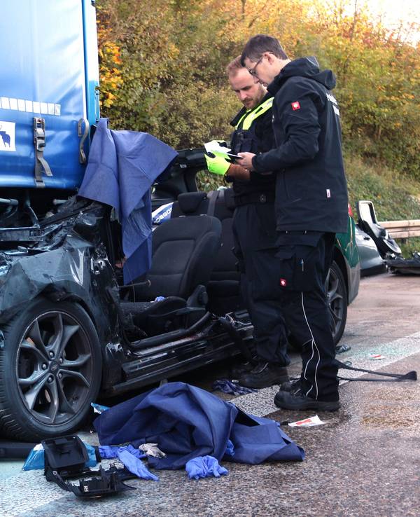 Einsatzkräfte der Polizei arbeiten an einem Unfallfahrzeug.