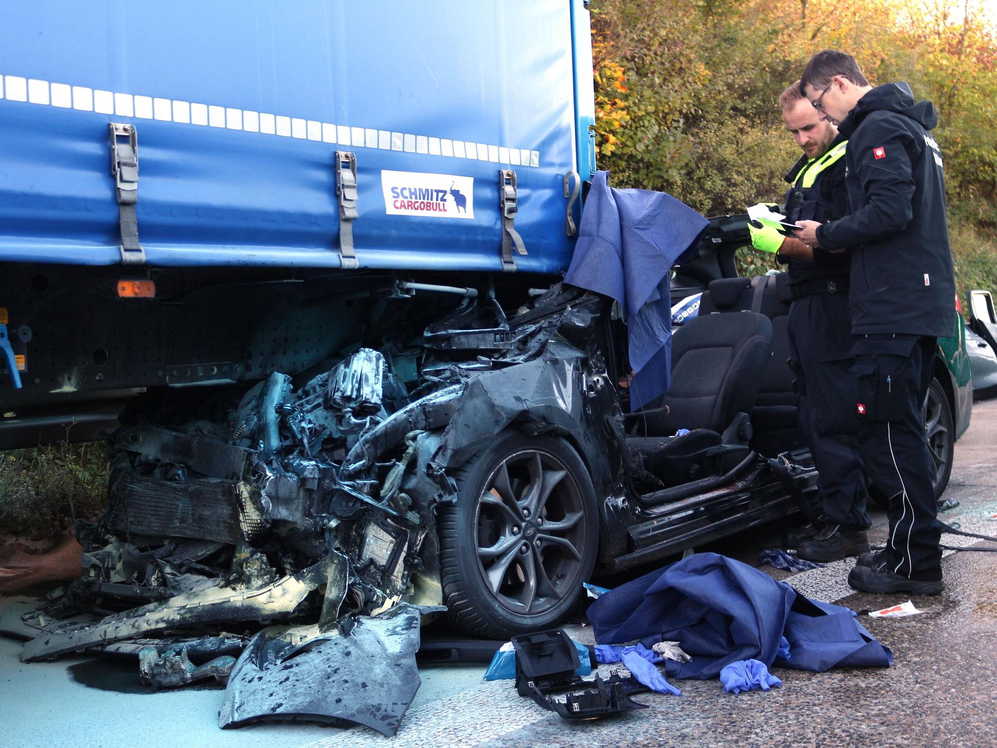 Einsatzkräfte der Polizei arbeiten an einem Unfallfahrzeug.