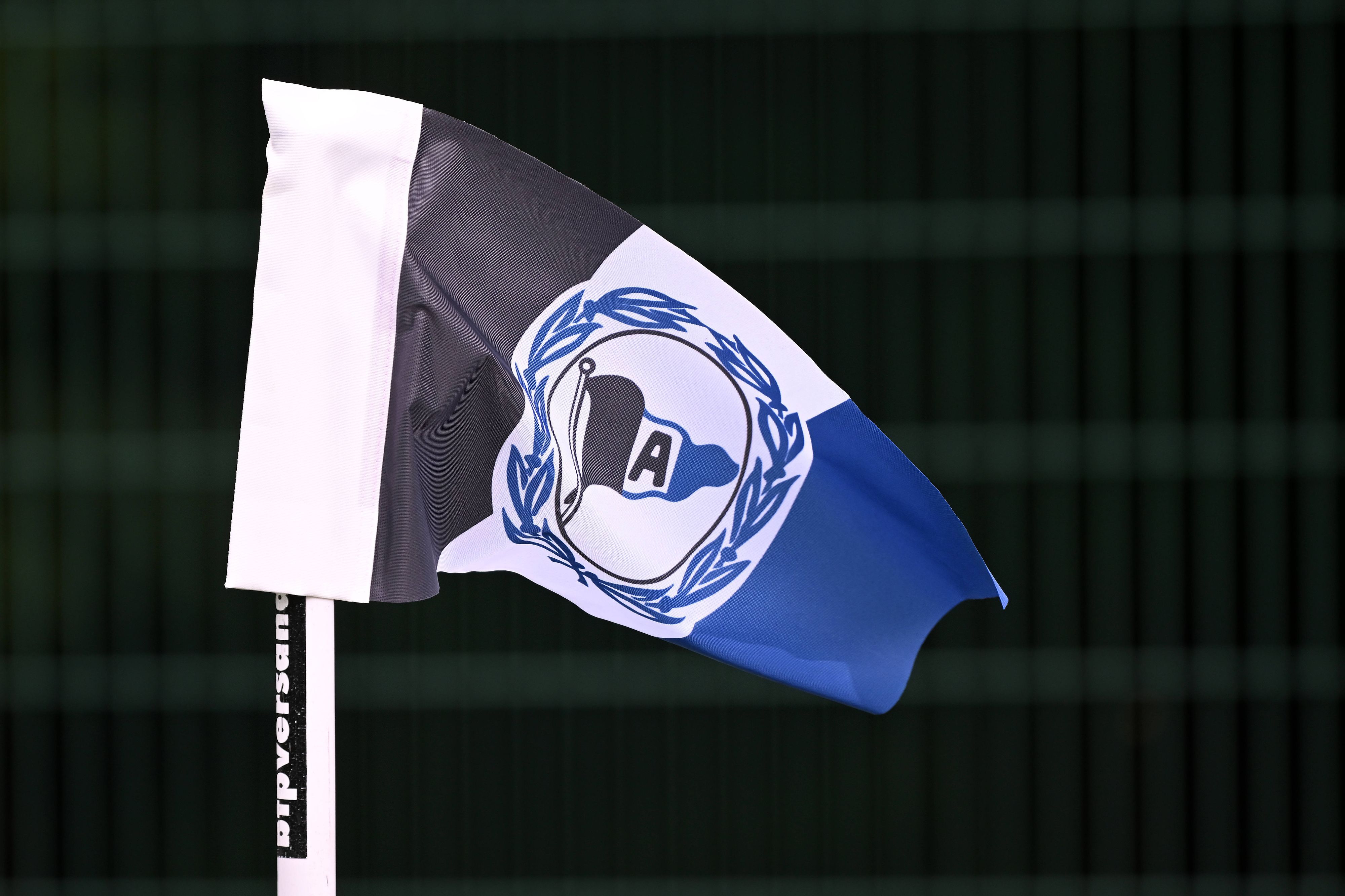 Eckfahne mit dem Logo von Arminia Bielefeld vor scharzem Hintergrund.