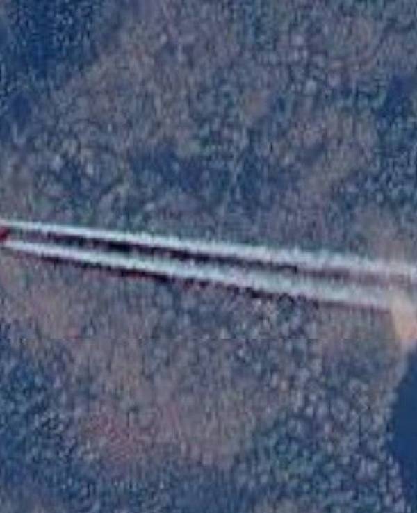 Über einem Waldstück in Bedburg-Hau (Kreis Kleve) ist ein bunt leuchtendes Flugzeug zu sehen.