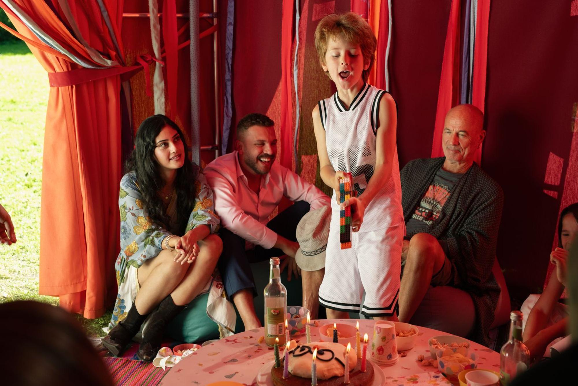 Nachdem ihm seine Mutter das Spielzeuggewehr weggenommen hat, baut sich Theo (Levin Wopp, zweiter von rechts) einfach eins aus Legosteinen. Sofia (Sogol Faghani), Timo (Edin Hasanović, zweiter von links) und Hans (Heiner Lauterbach) finden es, anders als Marlene, lustig. (Bild: Nadja Klier/Netflix)