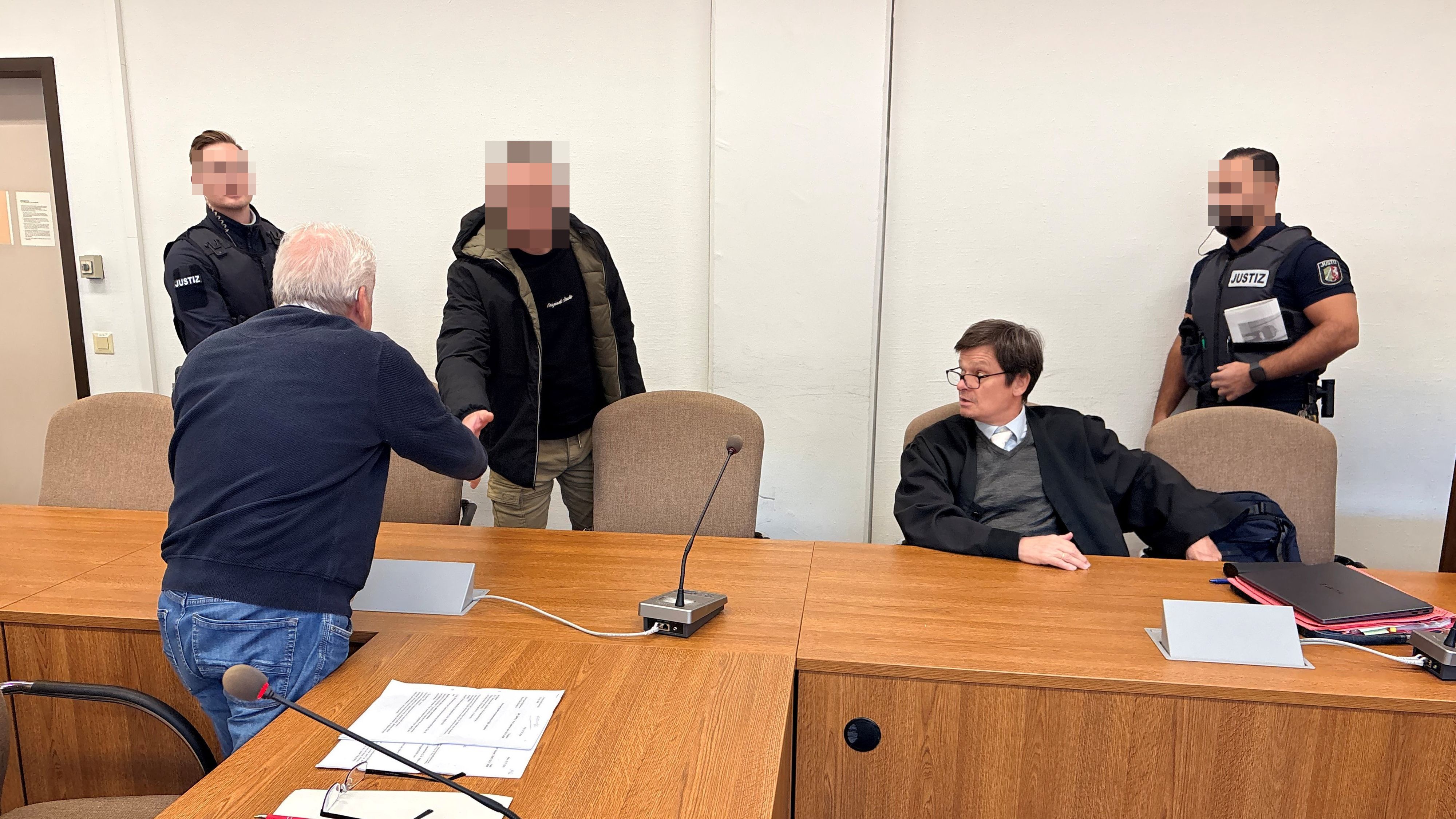 Landgericht Köln: Der Beschuldigte begrüßt Dolmetscher Bahadir Aksungur. Daneben Verteidiger Christian Kemperdick.