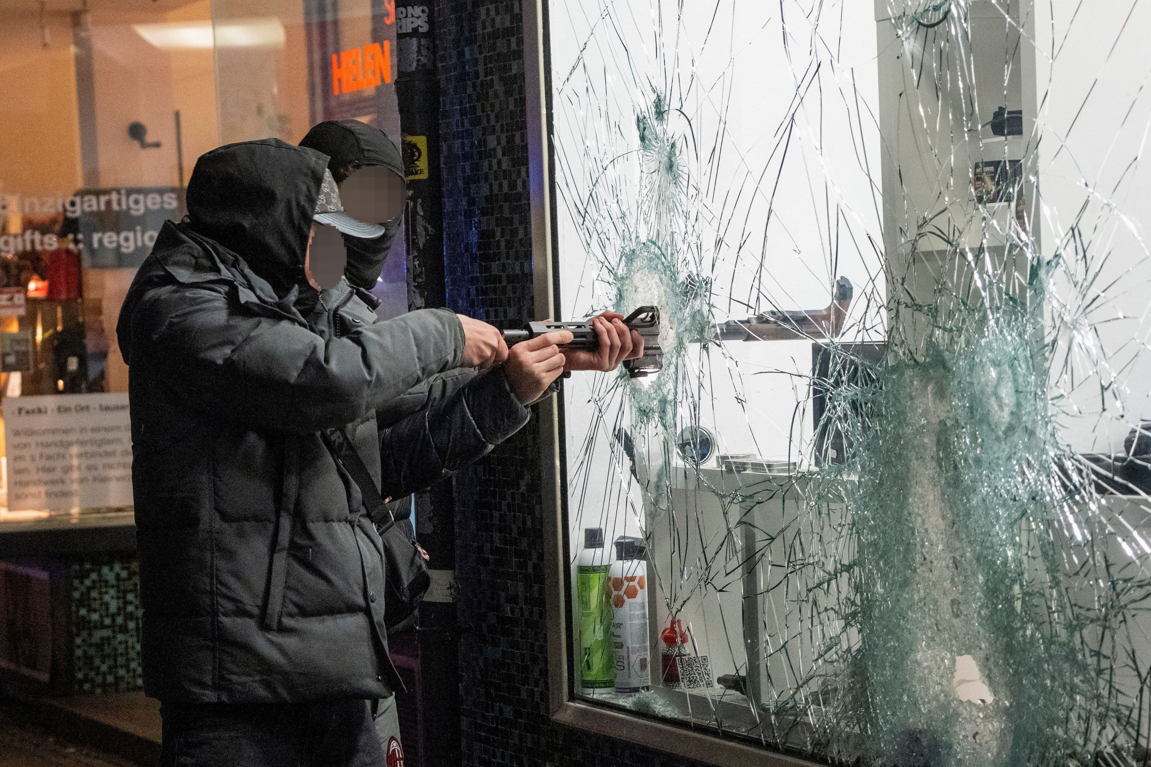 Zwei junge Männer stehlen durch die eingeschlagene Scheibe von einem Waffengeschäft in Frankfurt eine Waffe.