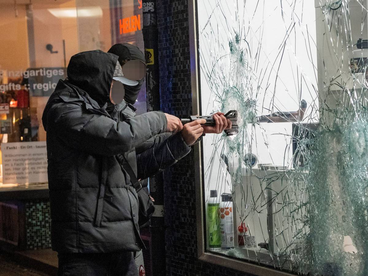 Zwei junge Männer stehlen durch die eingeschlagene Scheibe von einem Waffengeschäft in Frankfurt eine Waffe.