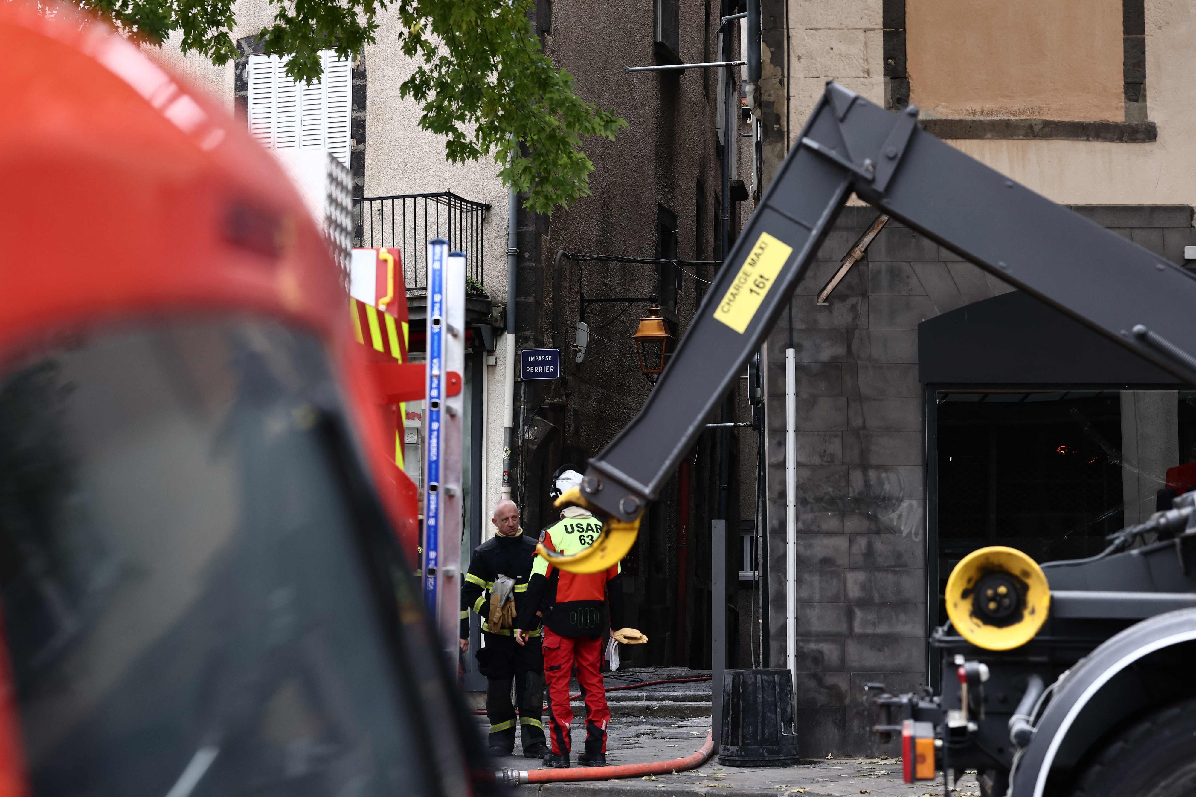 Zwei Feuerwehrmänner stehen an einem Haus, in dem es gebrannt hat.