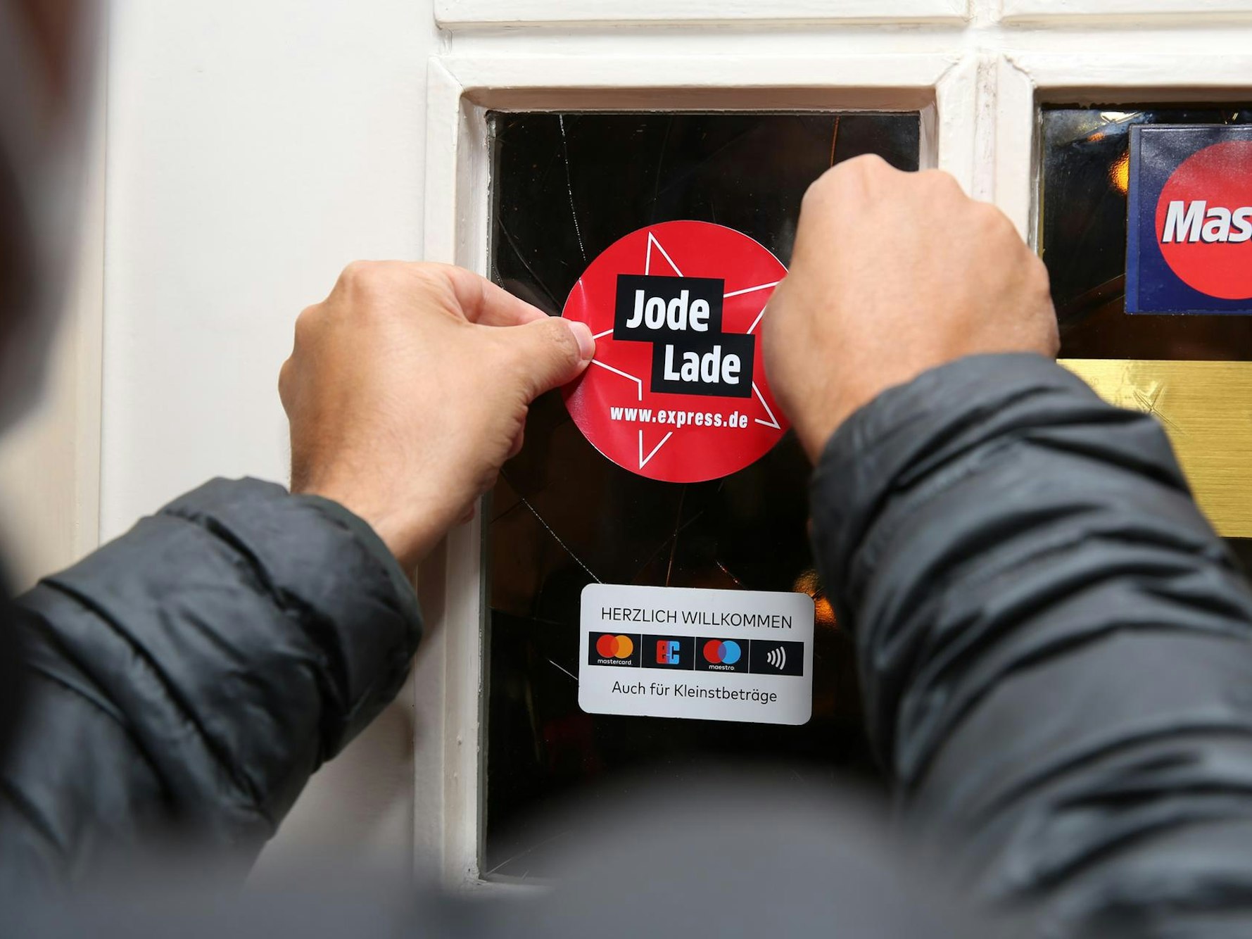 Mann bringt Jode-Lade-Siegel in Restaurant in Köln an.