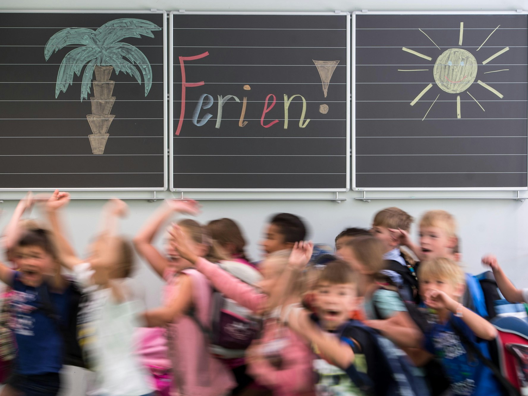 Grundschulkinder vor einer bemalten Tafel.