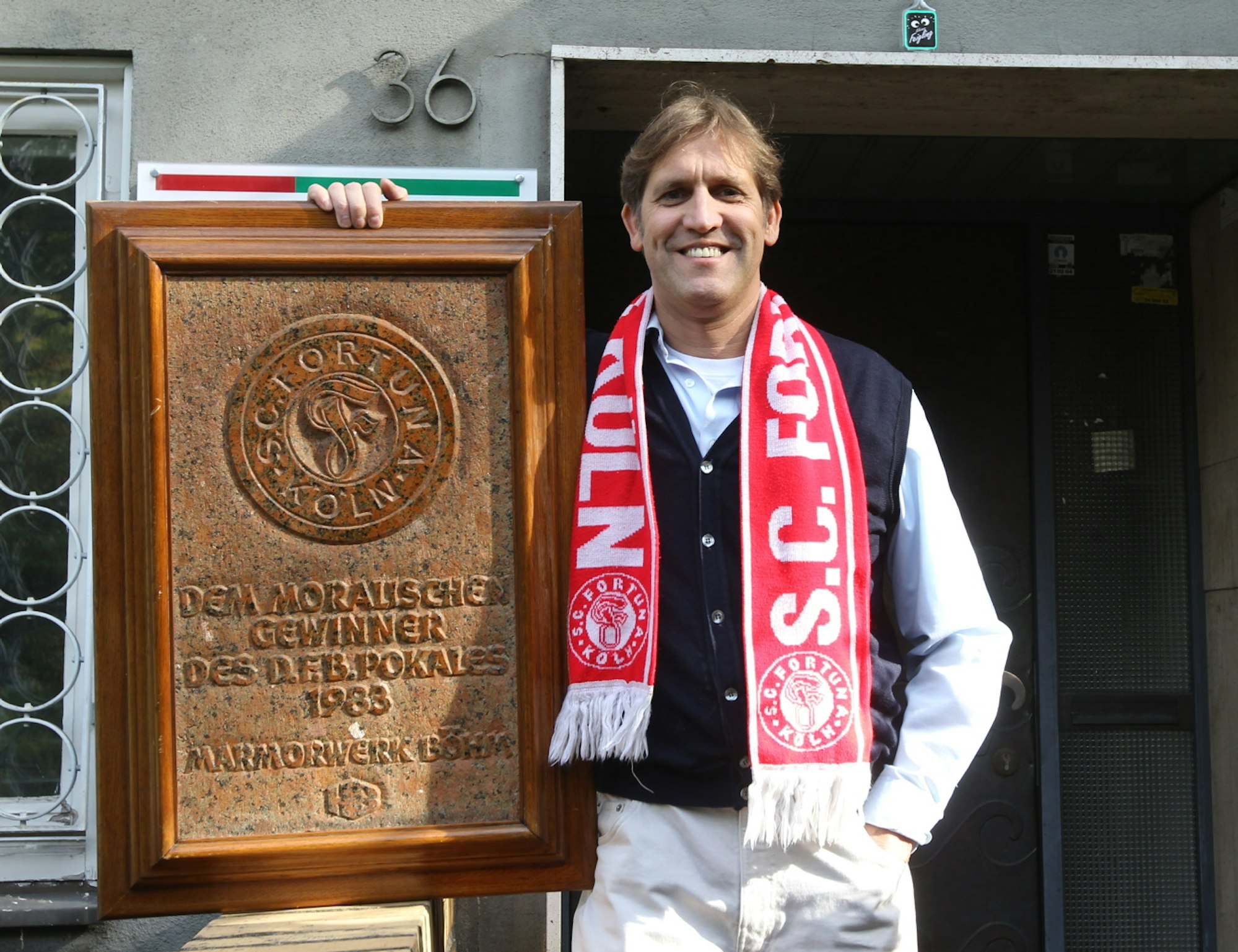 Künstler Cornel Wachter hält eine Gedenktafel in die Kamera.