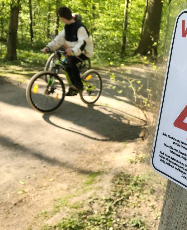 Ein Schild warnt in einem Wald vor Zecken.