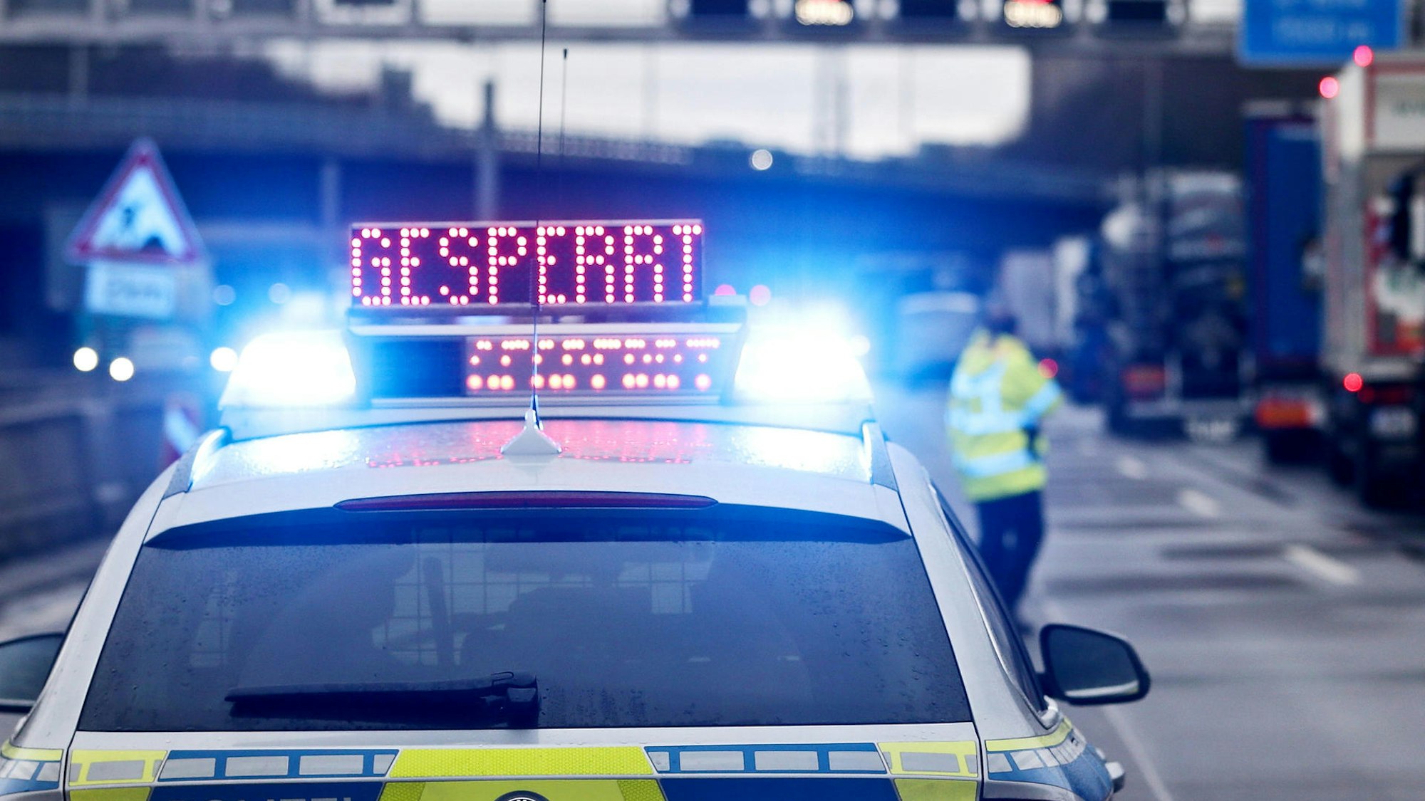 Ein Streifenwagen steht auf einer Autobahn, auf seinem Dach leuchtet das Wort „gesperrt“.