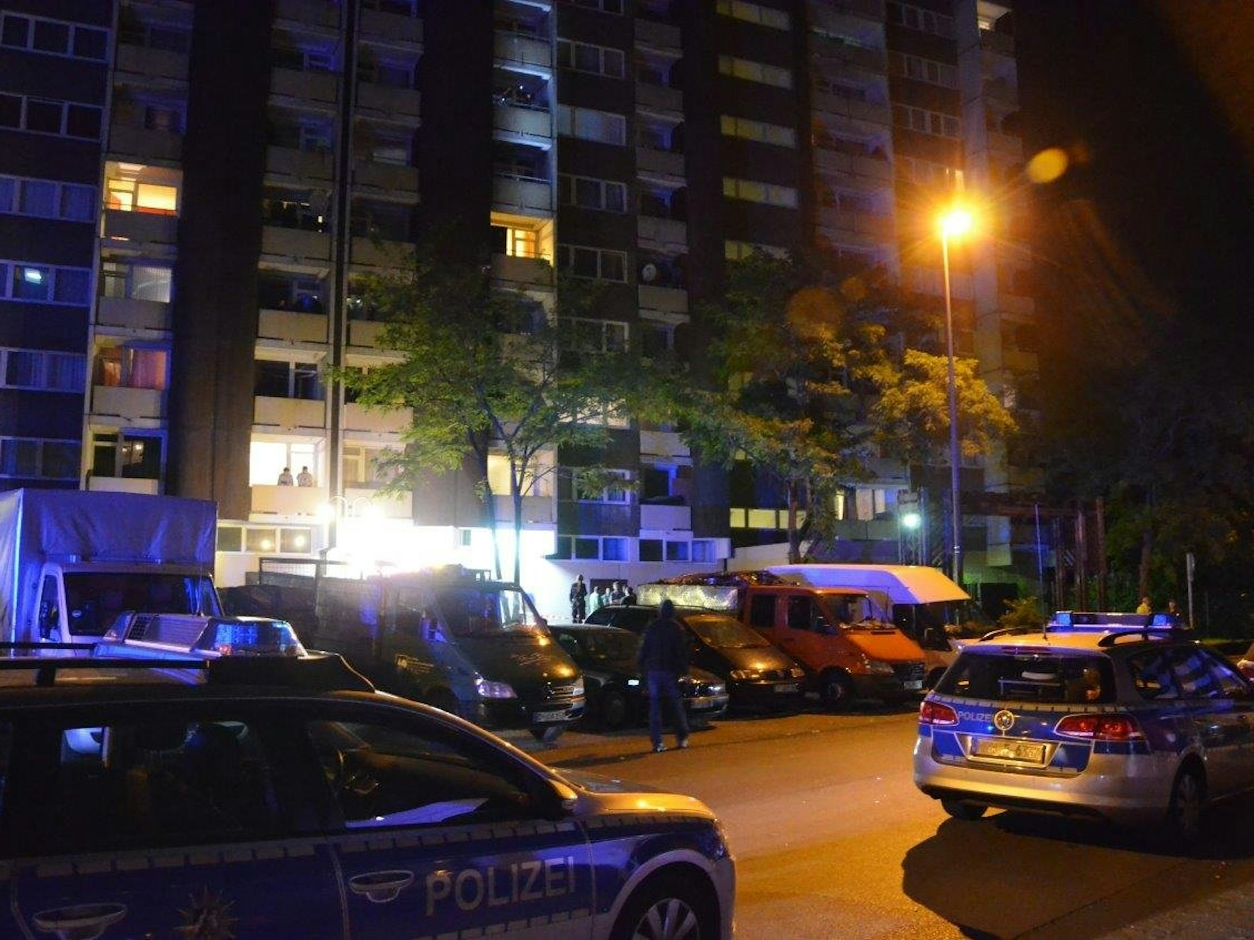 Polizeiwagen stehen auf einem Parkplatz vor einem Hochhaus.