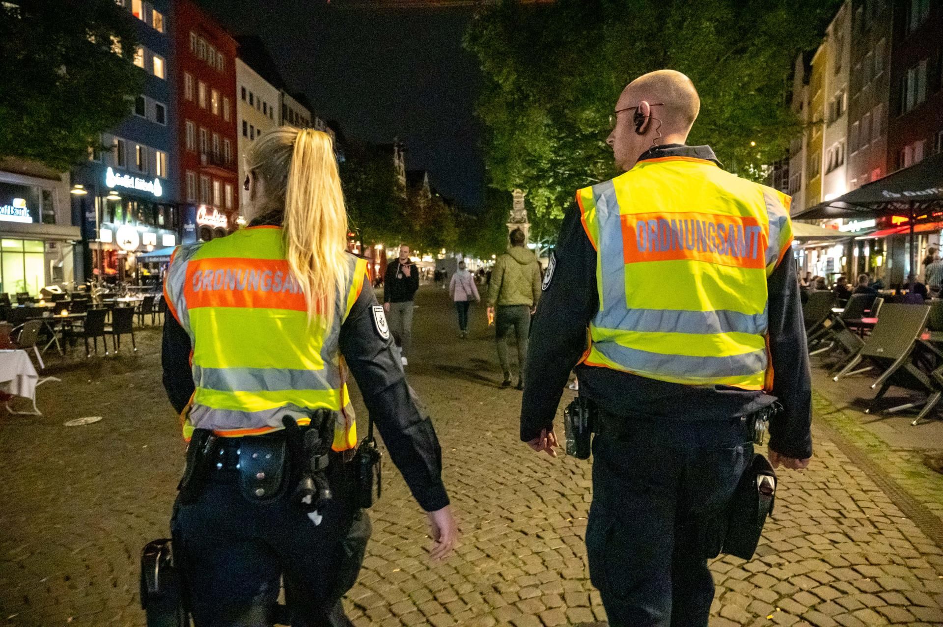 Eine Mitarbeiterin und ein Mitarbeiter des Ordnungsamtes laufen durch die Kölner Altstadt.