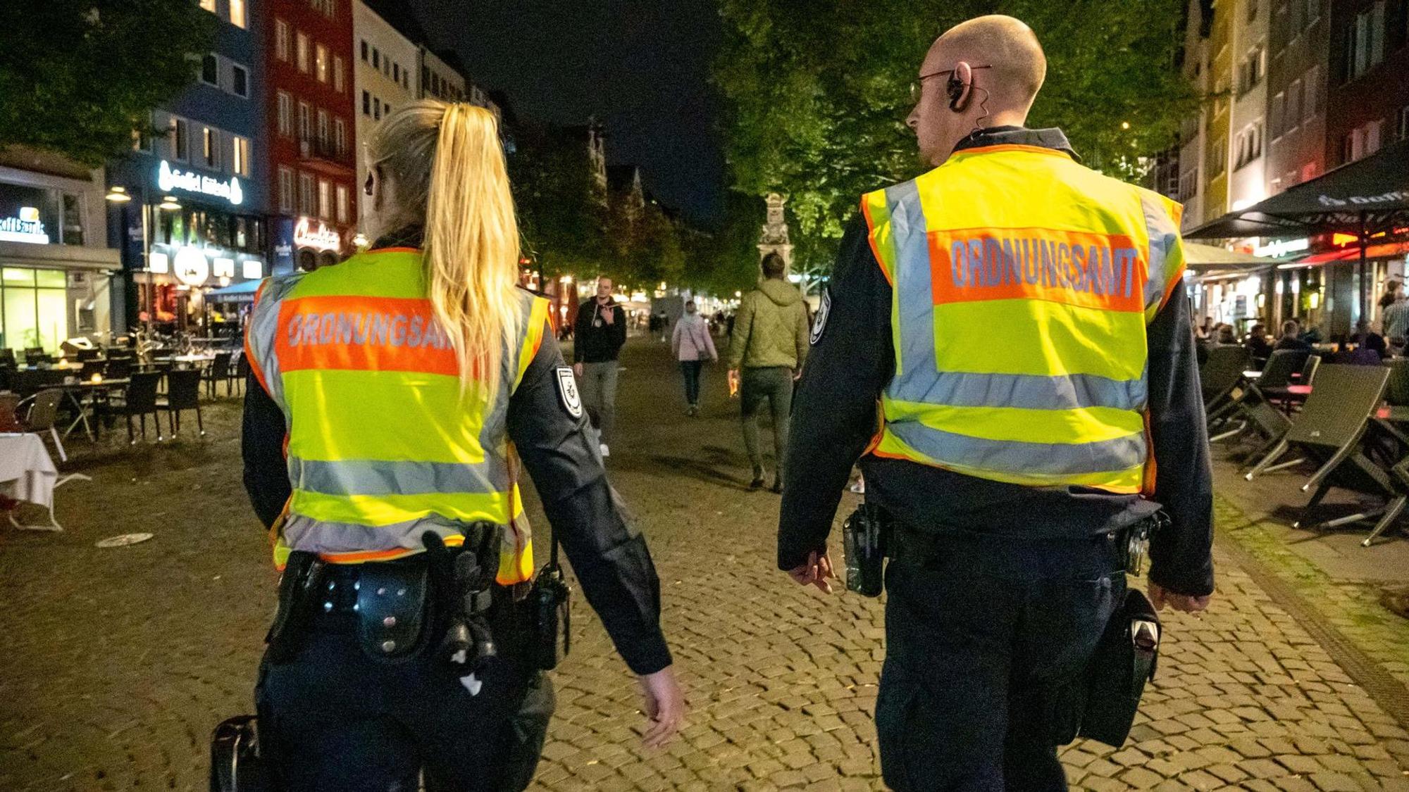 Eine Mitarbeiterin und ein Mitarbeiter des Ordnungsamtes laufen durch die Kölner Altstadt.