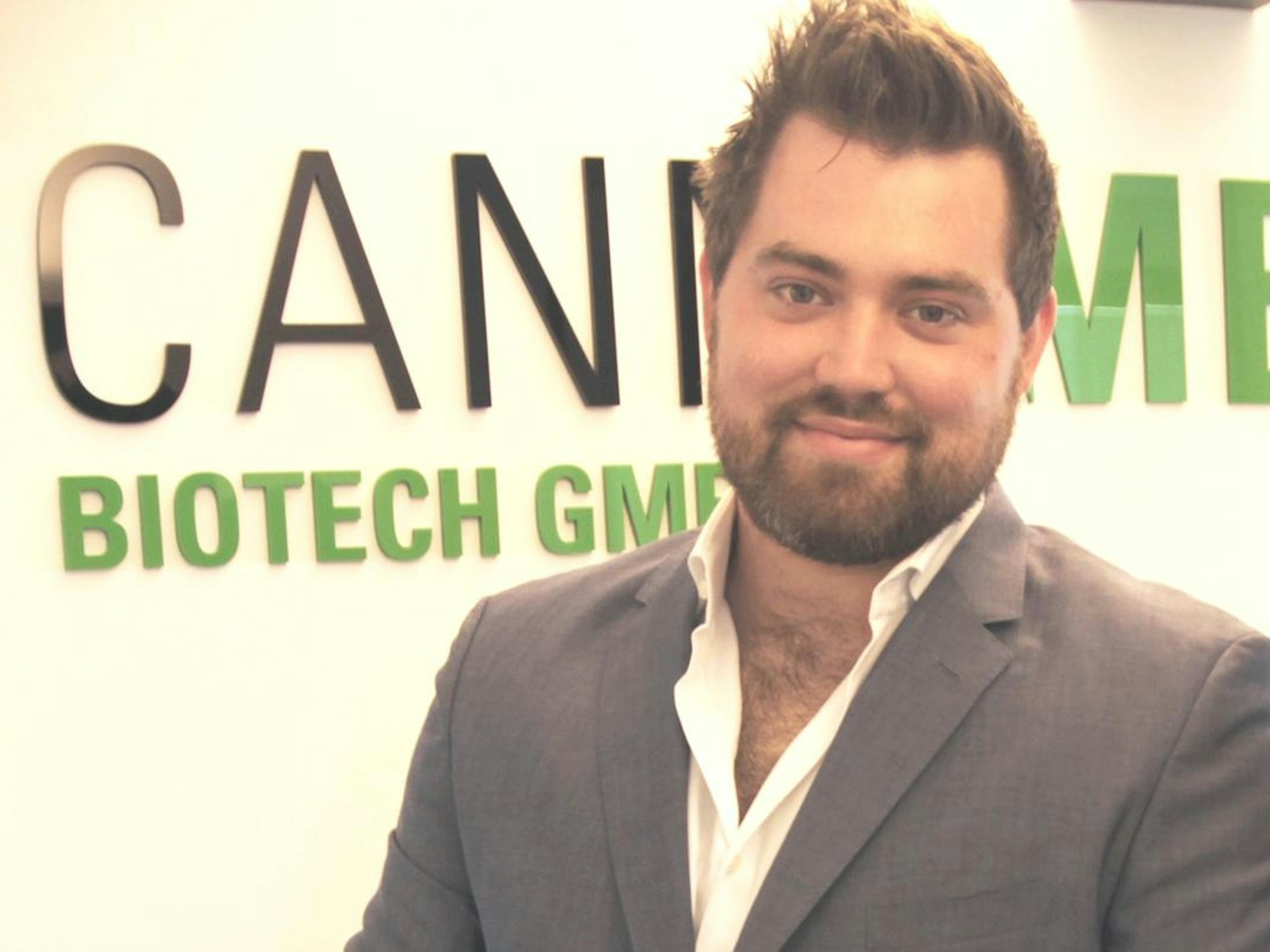 David Henn und Susanne Simon stehen vor einer Wand mit dem Schriftzug „Cannamedical Biotech GmbH“.