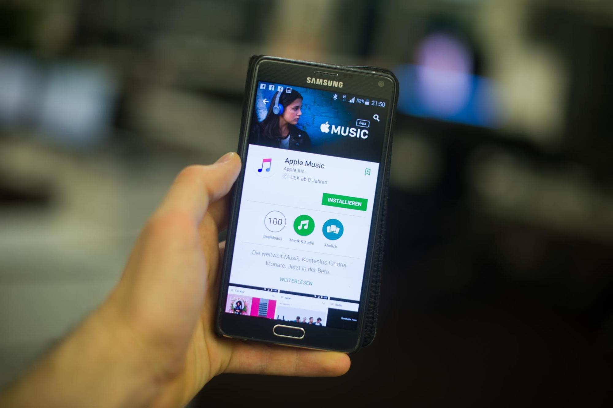 Hand hält Smartphone mit Apple Music auf dem Display.