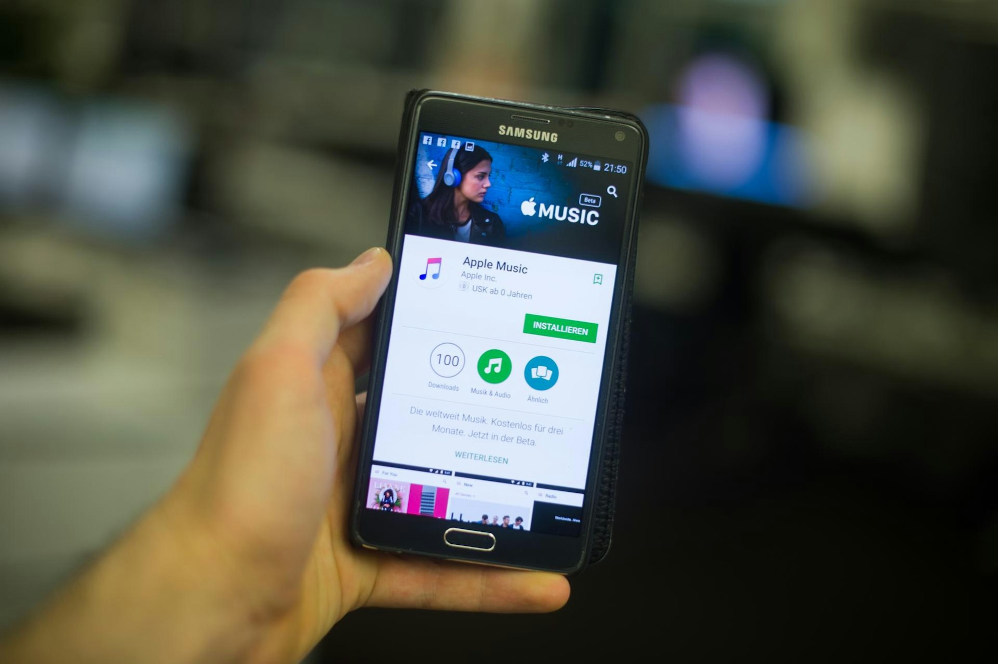 Hand hält Smartphone mit Apple Music auf dem Display.