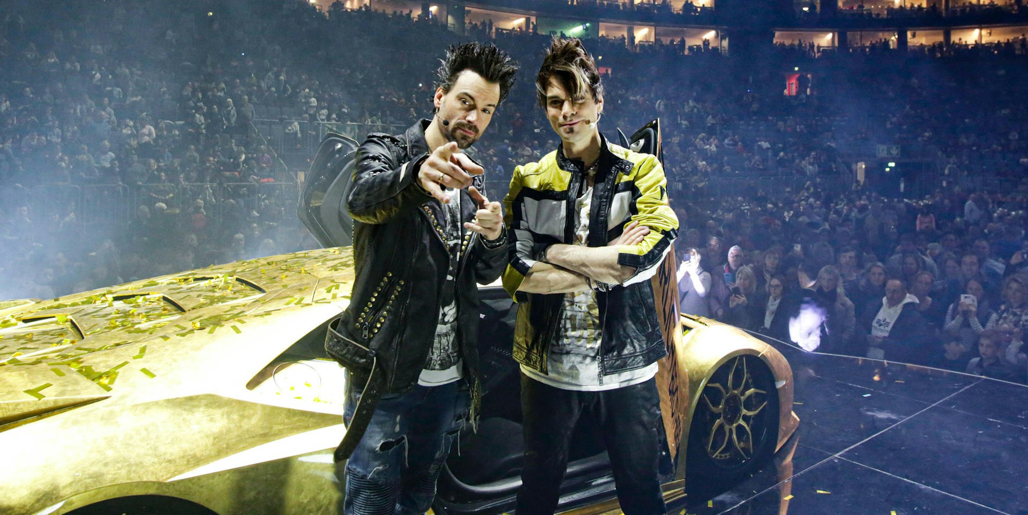 Andreas und Christian Ehrlich posieren in der Show-Pause vor ihrem goldenen Super-Flitzer in der Lanxess-Arena.