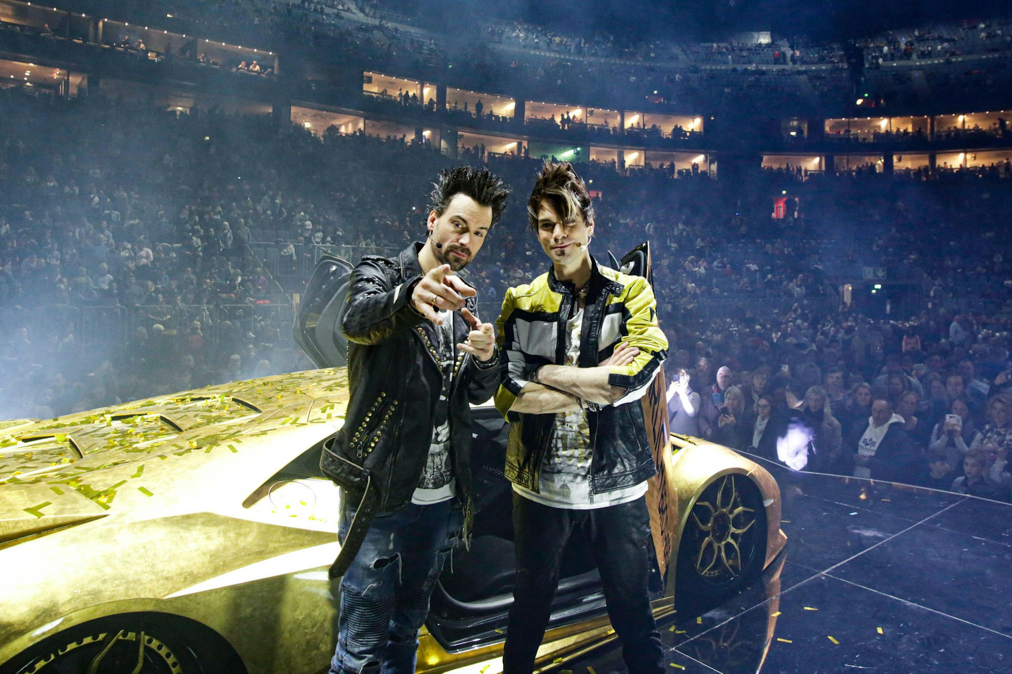 Andreas und Christian Ehrlich posieren in der Show-Pause vor ihrem goldenen Super-Flitzer in der Lanxess-Arena.