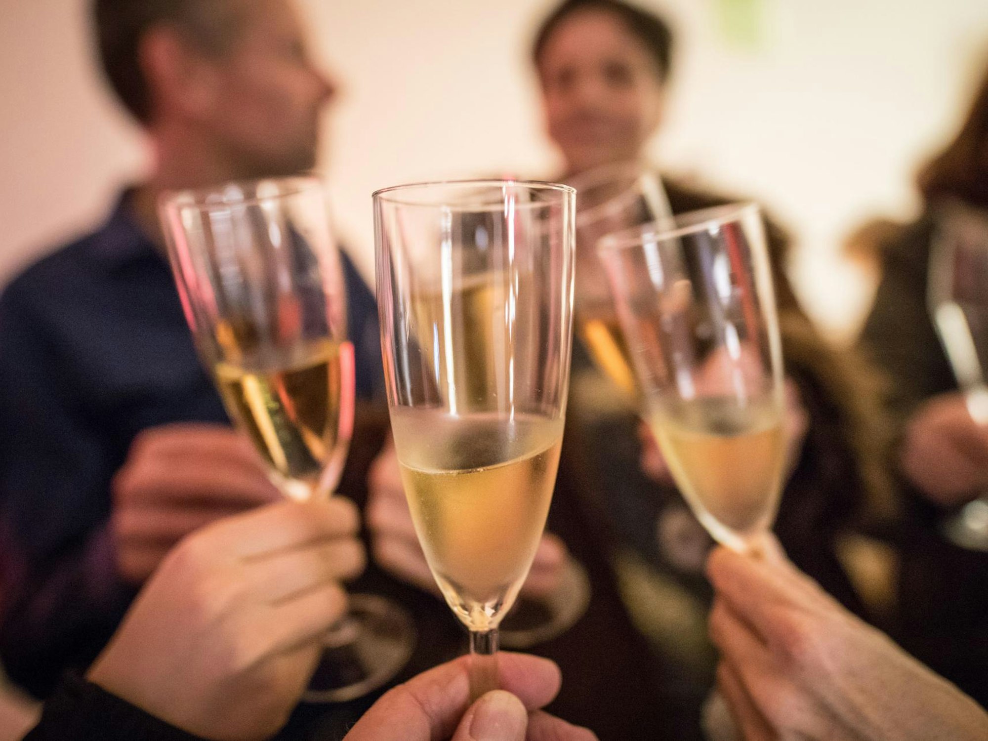 Leute prosten sich mit Sektgläsern zu.