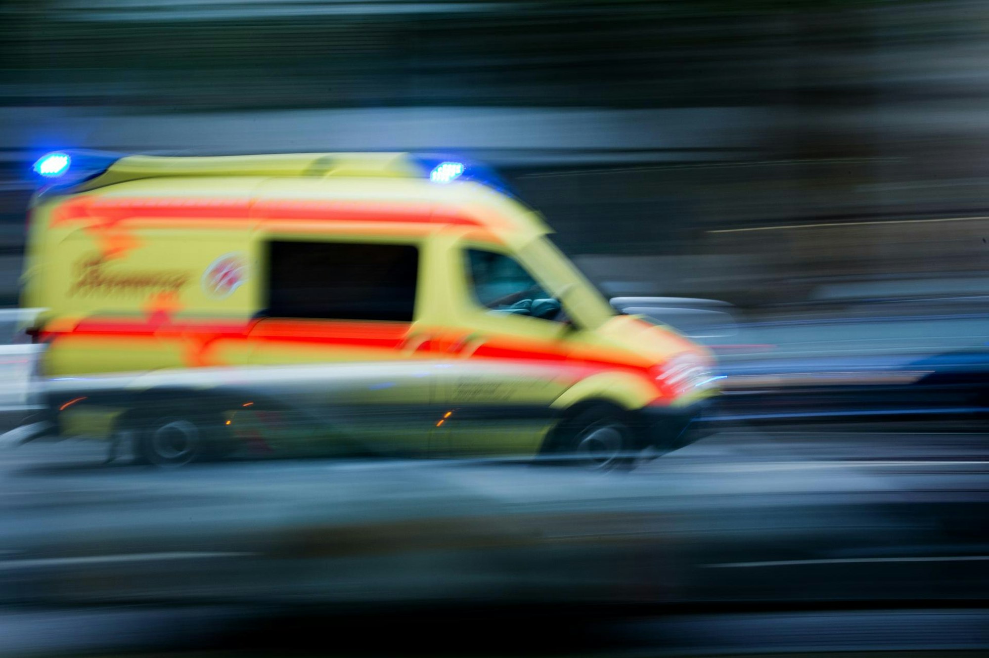 Ein Krankenwagen fährt mit Blaulicht über eine Straße.