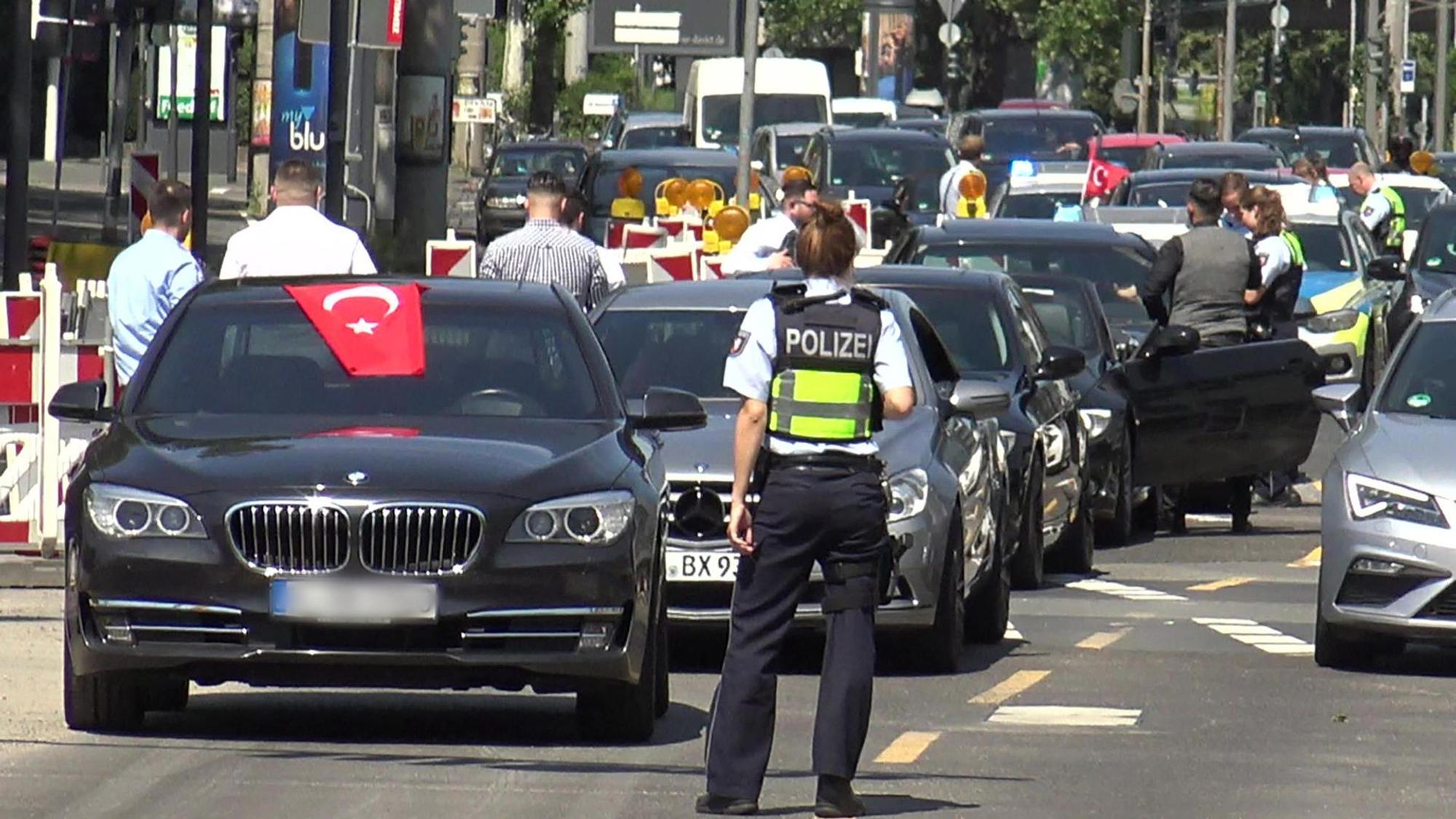 Eine Polizistin steht vor einer Fahrzeugkolonne einer Hochzeitsgesellschaft.