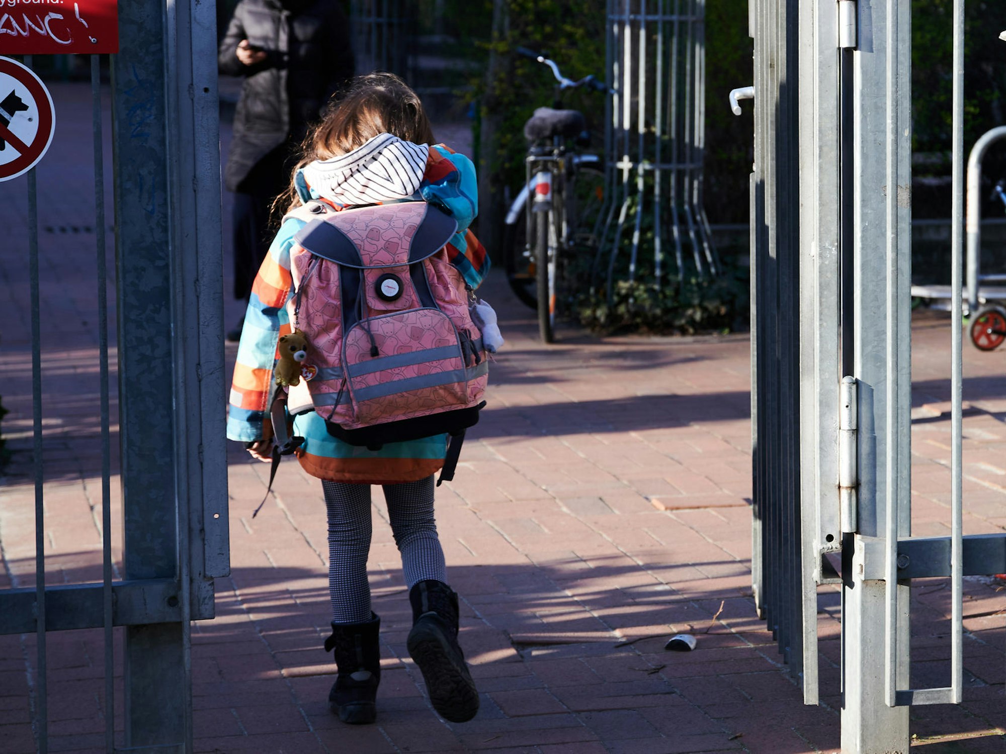 Köln: Grundschulkind betritt mit Schulranzen das Gelände.