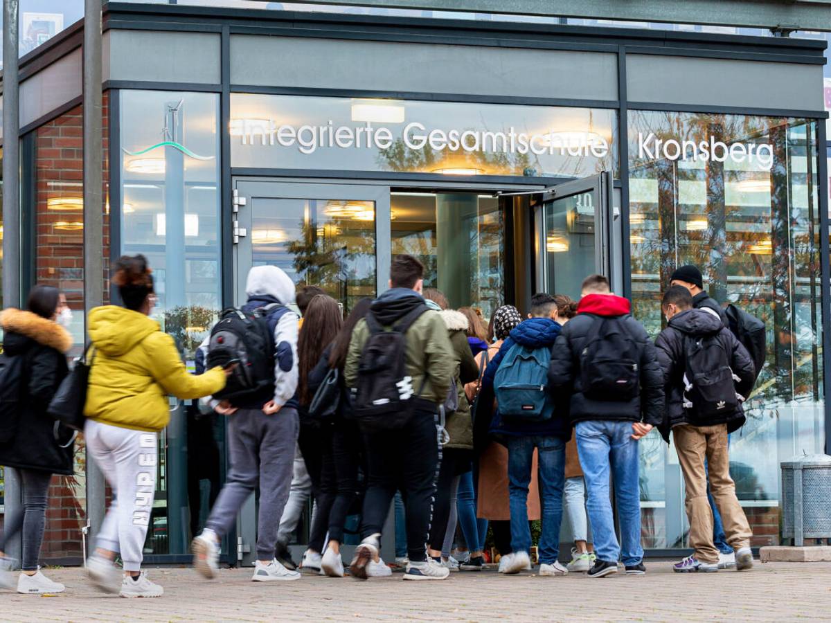 Schülerinnen und Schüler betreten eine Schule.