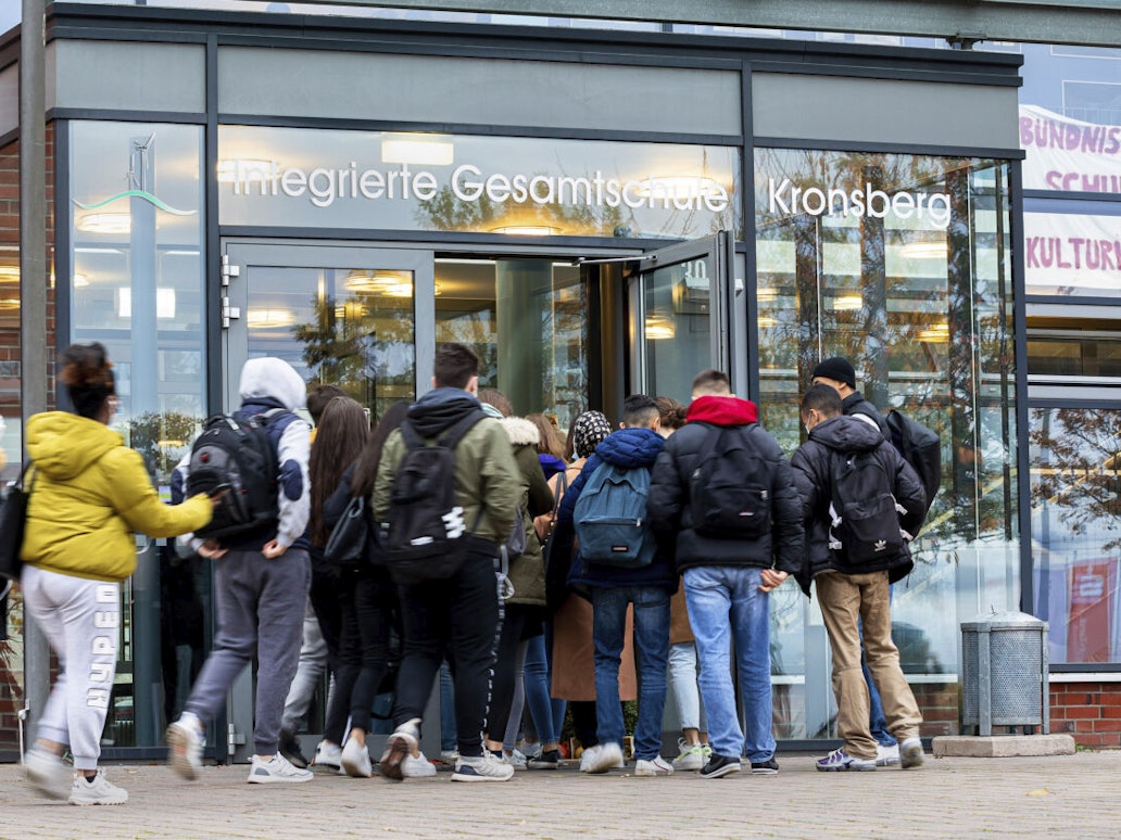 Schülerinnen und Schüler betreten eine Schule.