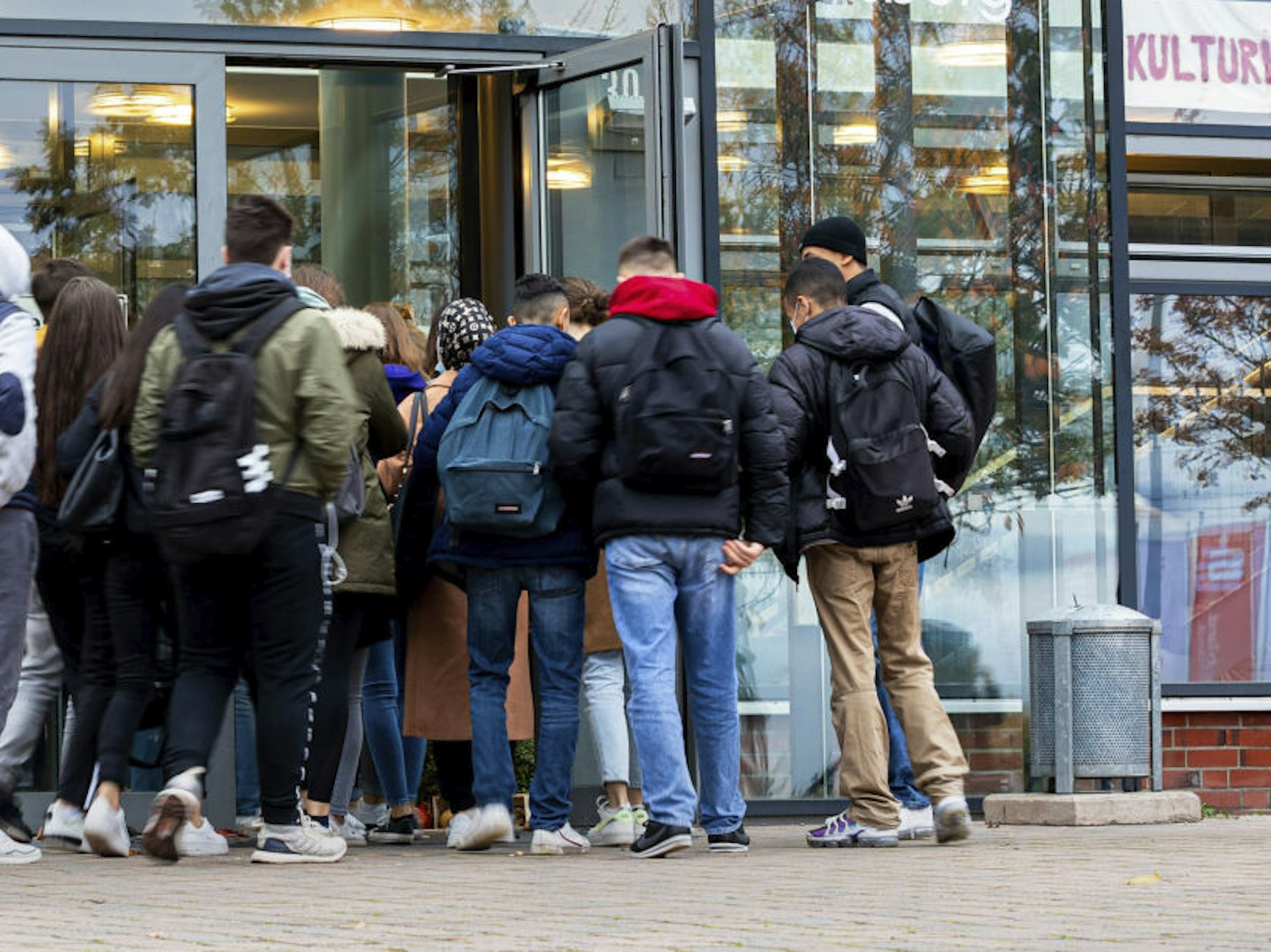 Schülerinnen und Schüler betreten eine Schule.