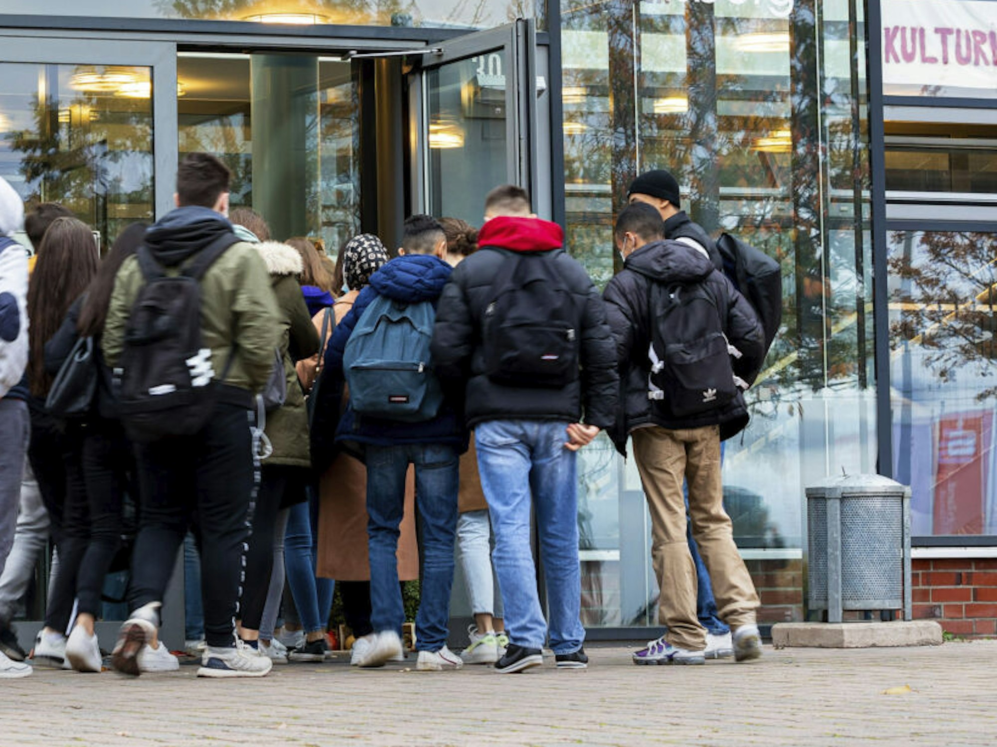 Schülerinnen und Schüler betreten eine Schule.