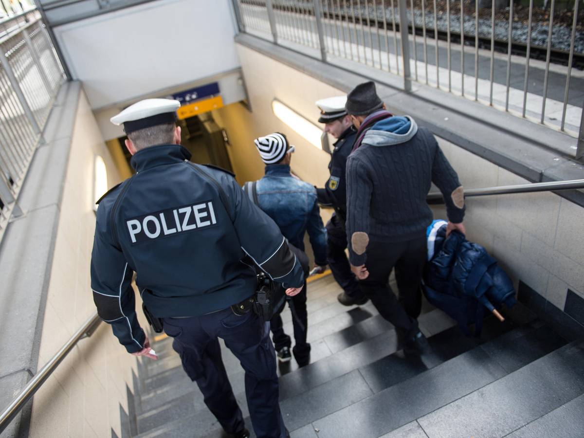Zwei Polizisten gehen gemeinsam mit zwei Männern eine Treppe im Kölner Hauptbahnhof runter.