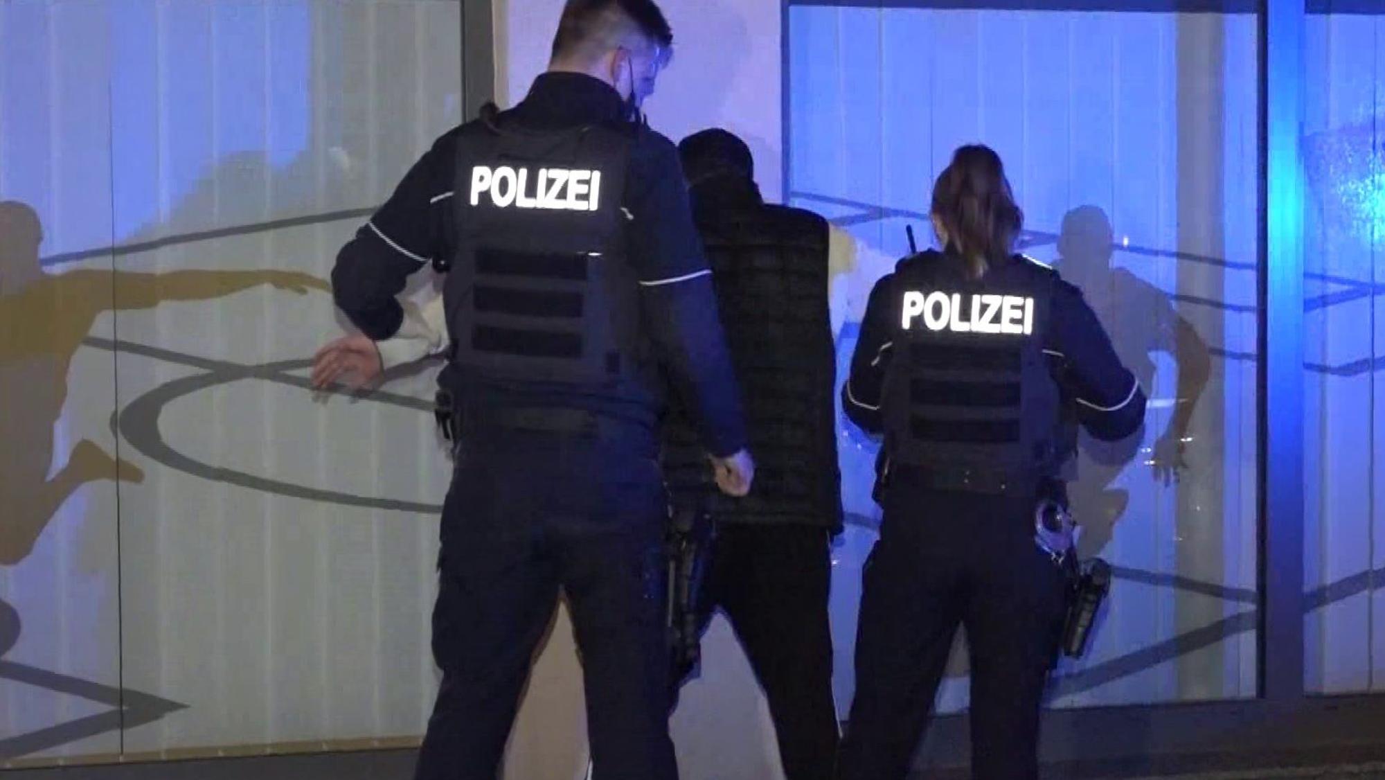 Ein Polizist und eine Polizistin bei einer Festnahme eines jungen Mannes.
