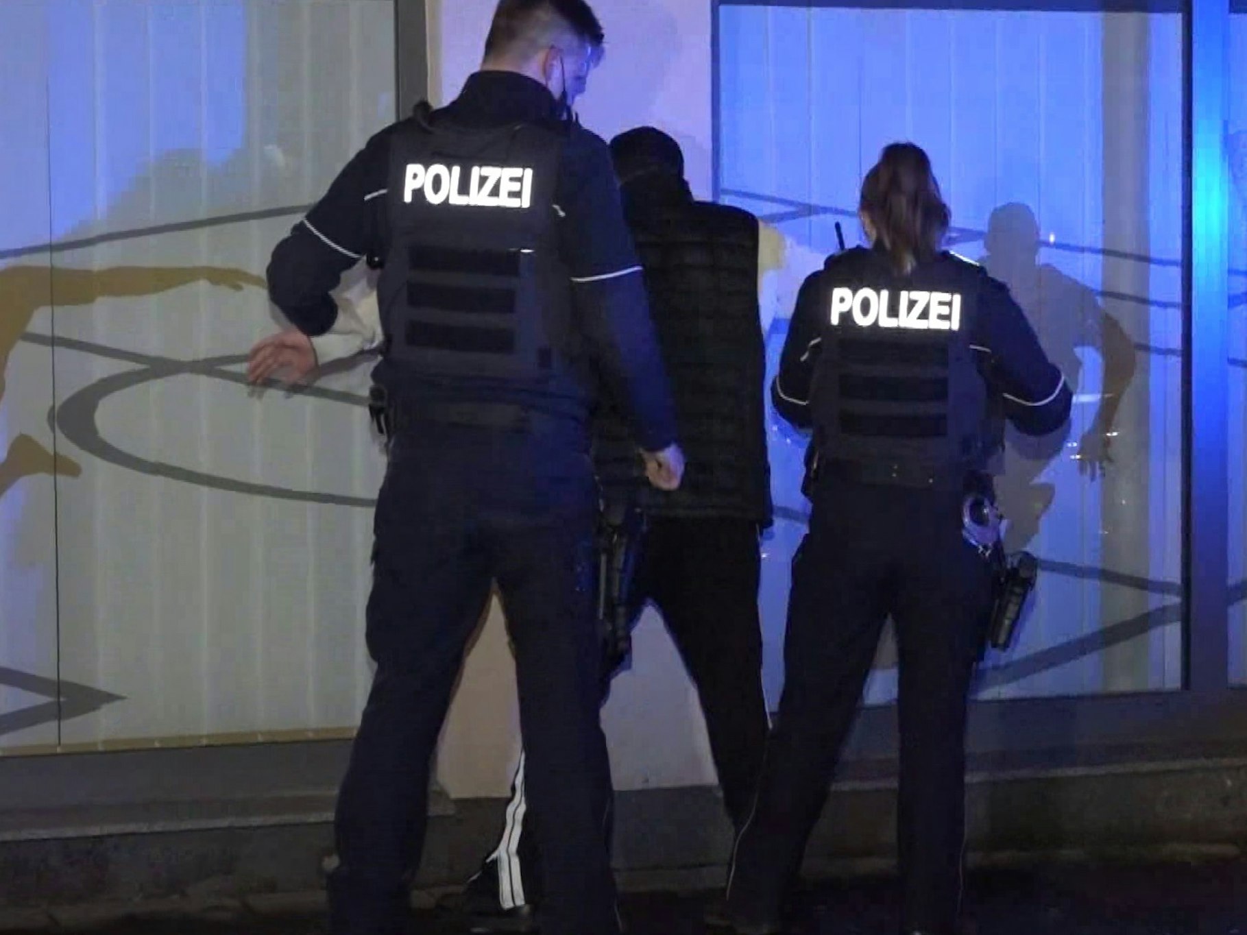 Ein Polizist und eine Polizistin bei einer Festnahme eines jungen Mannes.