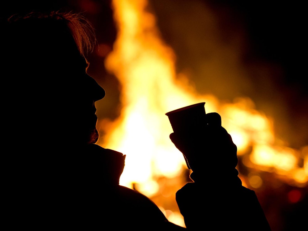 Die Silhouette eines Menschen setzt sich auf diesem undatierten Foto vor einem Feuer ab.
