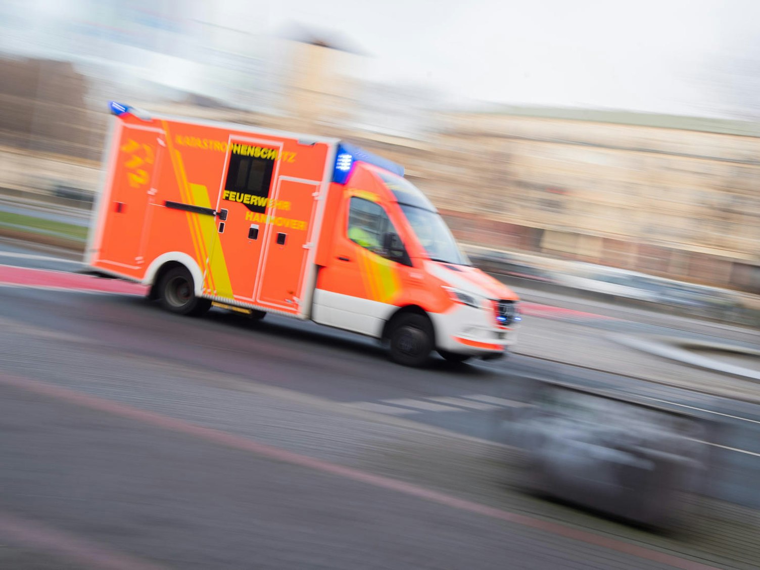 Ein Krankenwagen fährt mit Blaulicht auf einer Straße.