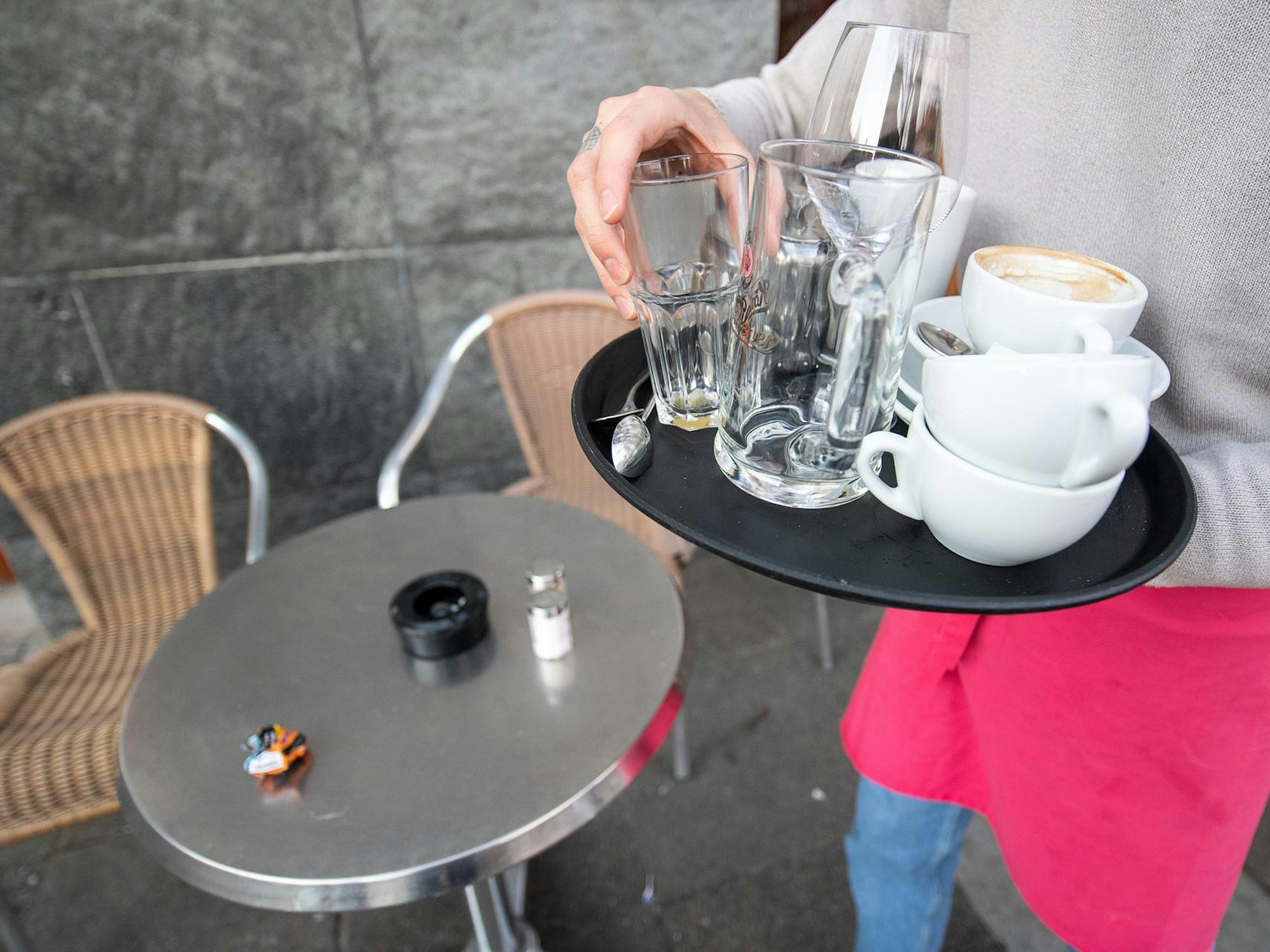 Eine Kellnerin trägt ein Tablett mit Getränken.